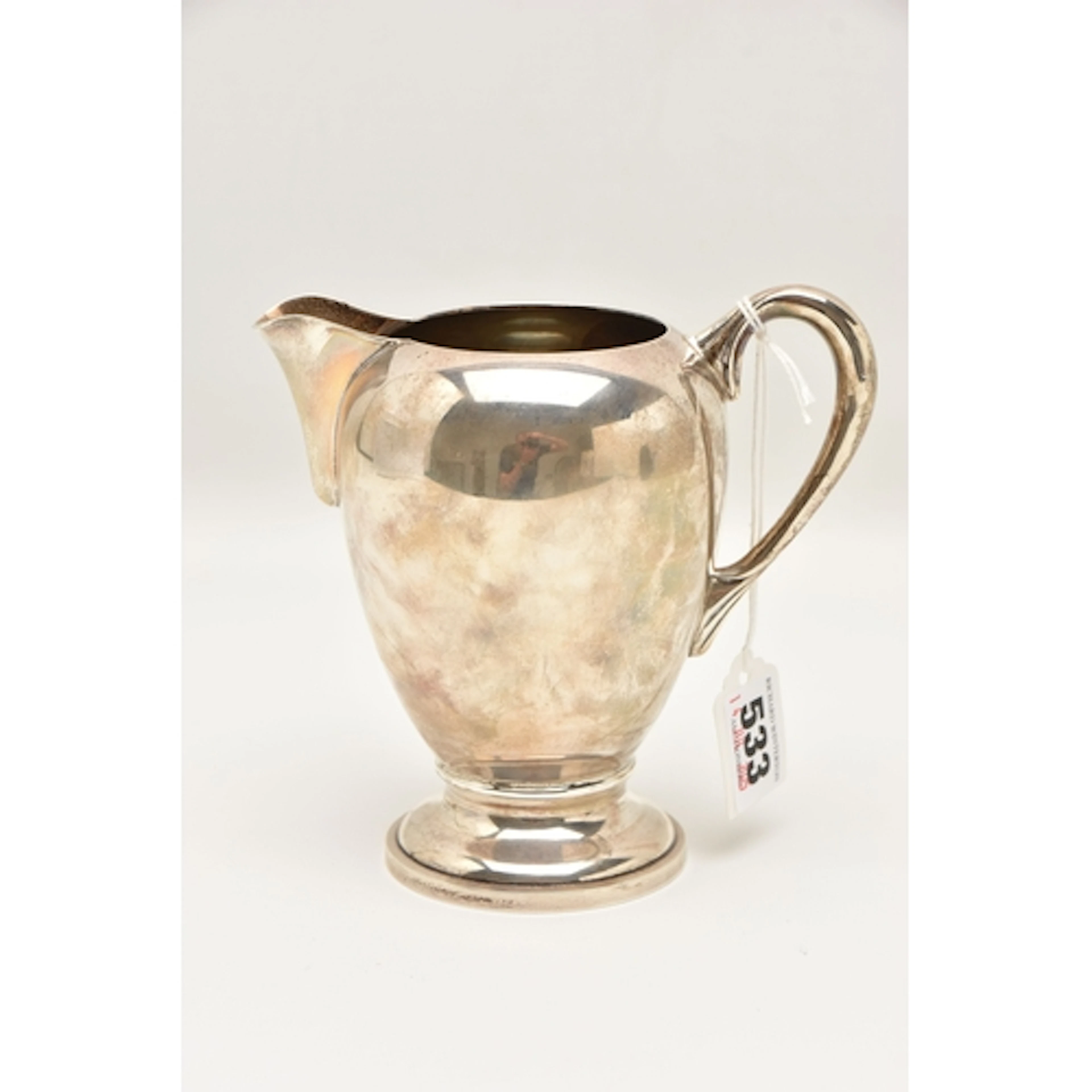 A CONTINENTAL WHITE METAL MILK JUG, polished form with scrol...