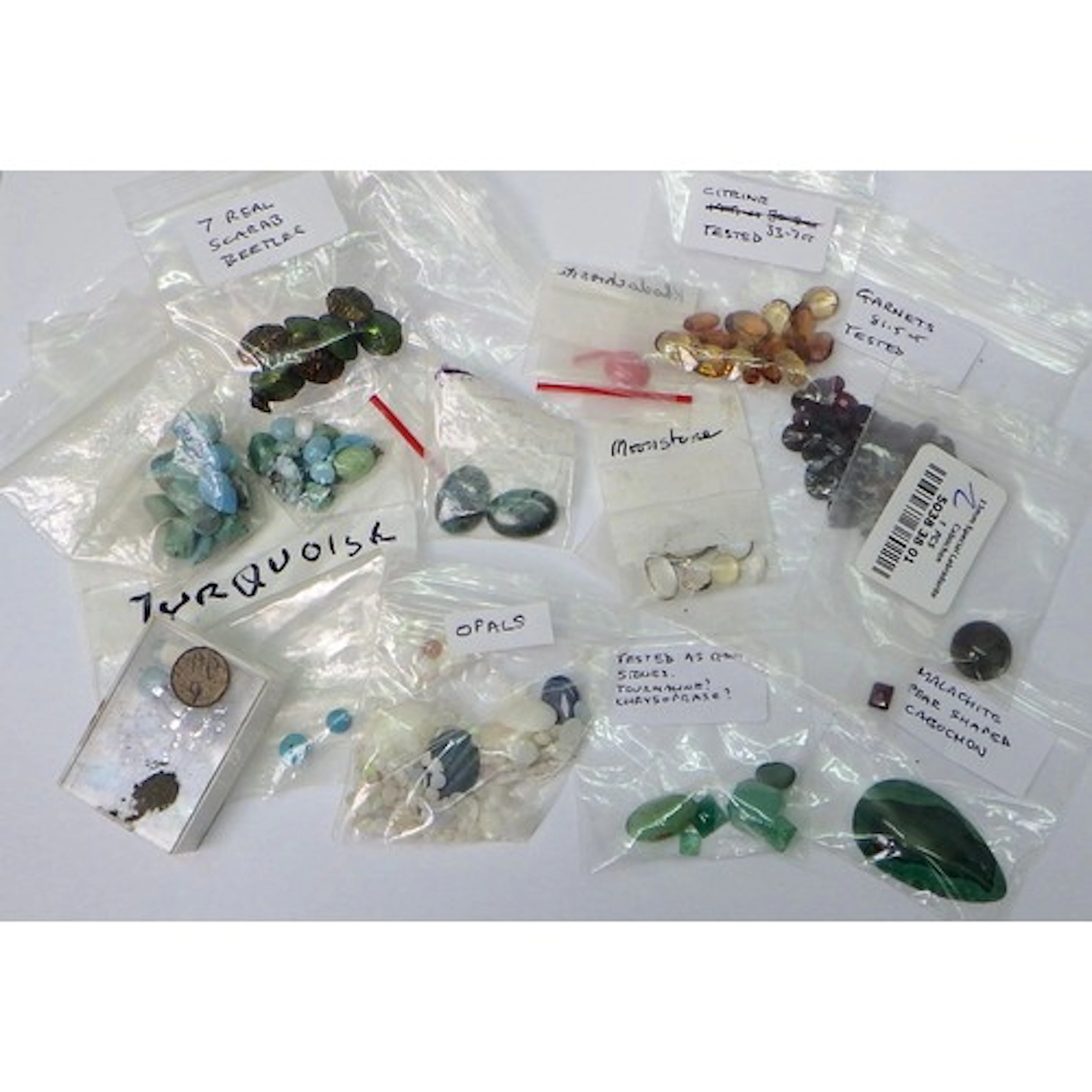 A collection of loose gem stones featuring garnet, citrine, ...