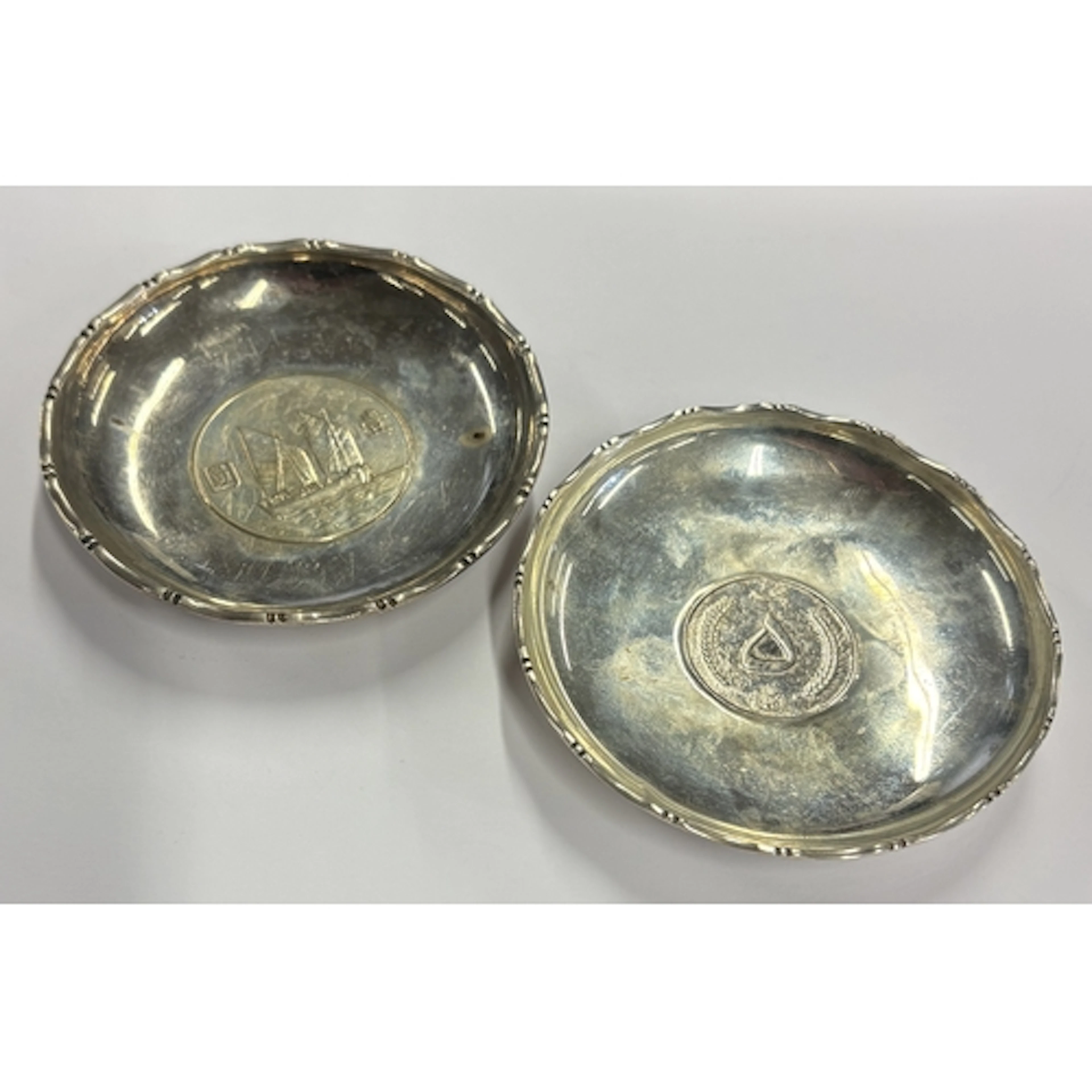 A pair of circular Chinese silver pin dishes set with coins....