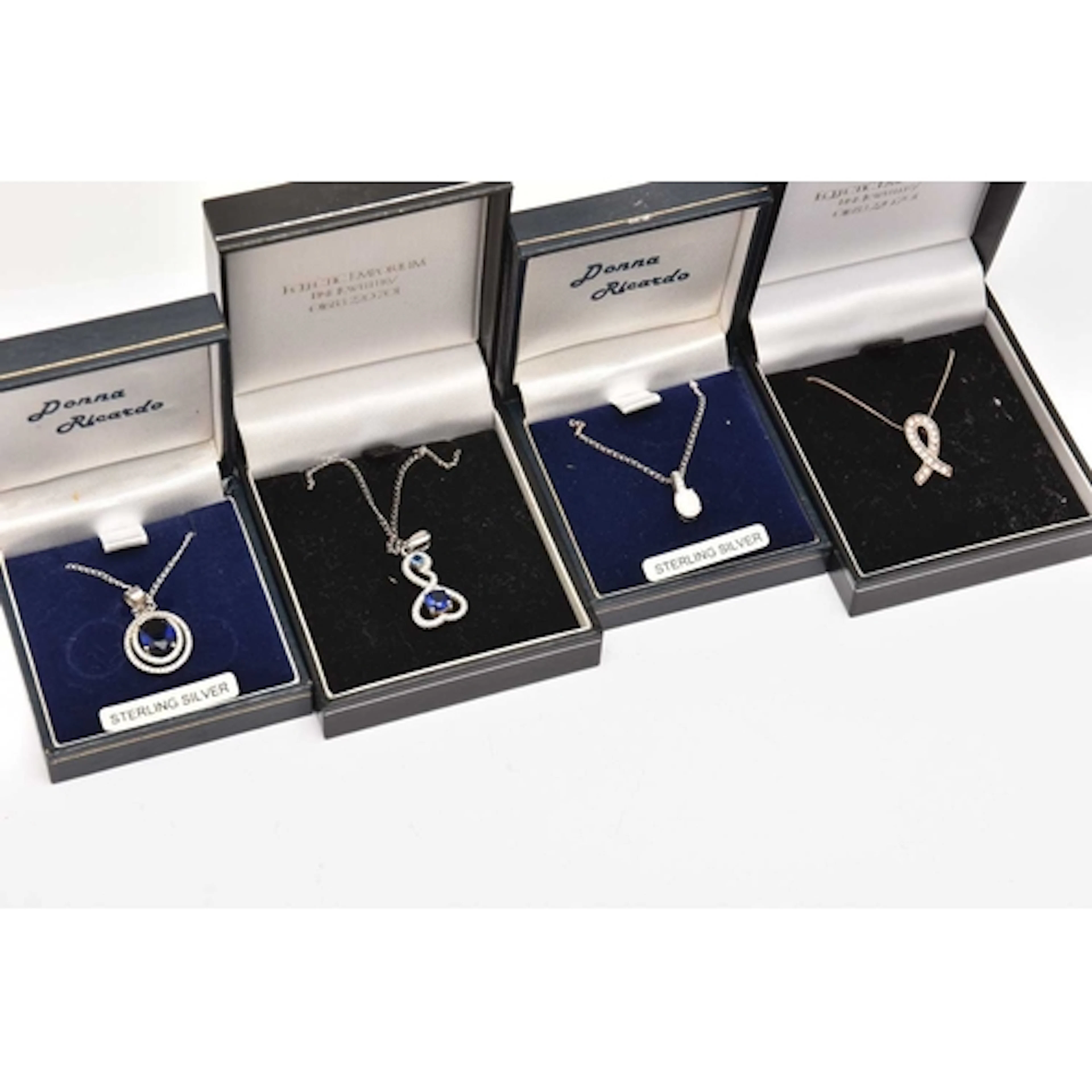 FOUR BOXED PENDANT NECKLACES, white metal gem set pendants w...