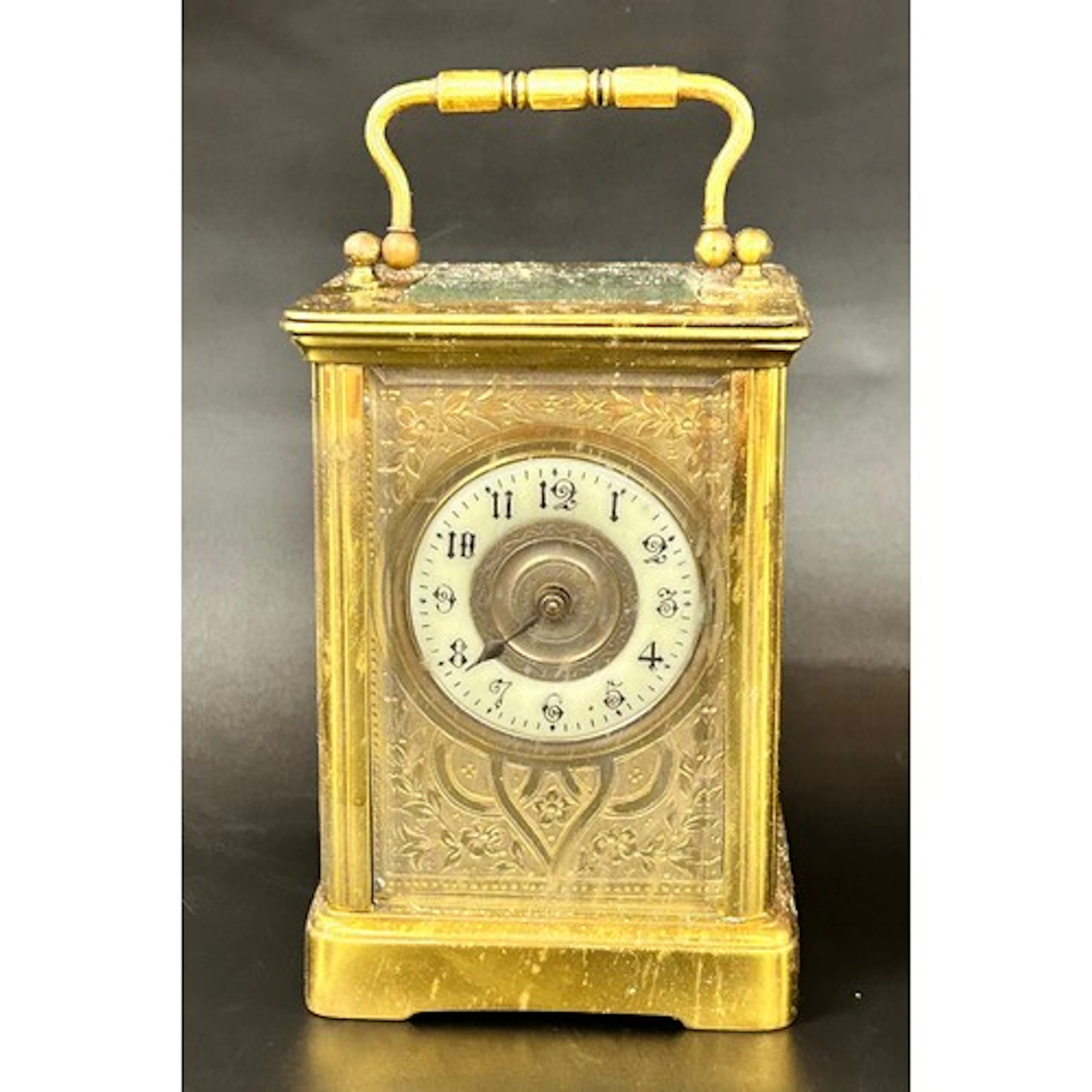 A brass carriage clock with decorative floral front panel an...