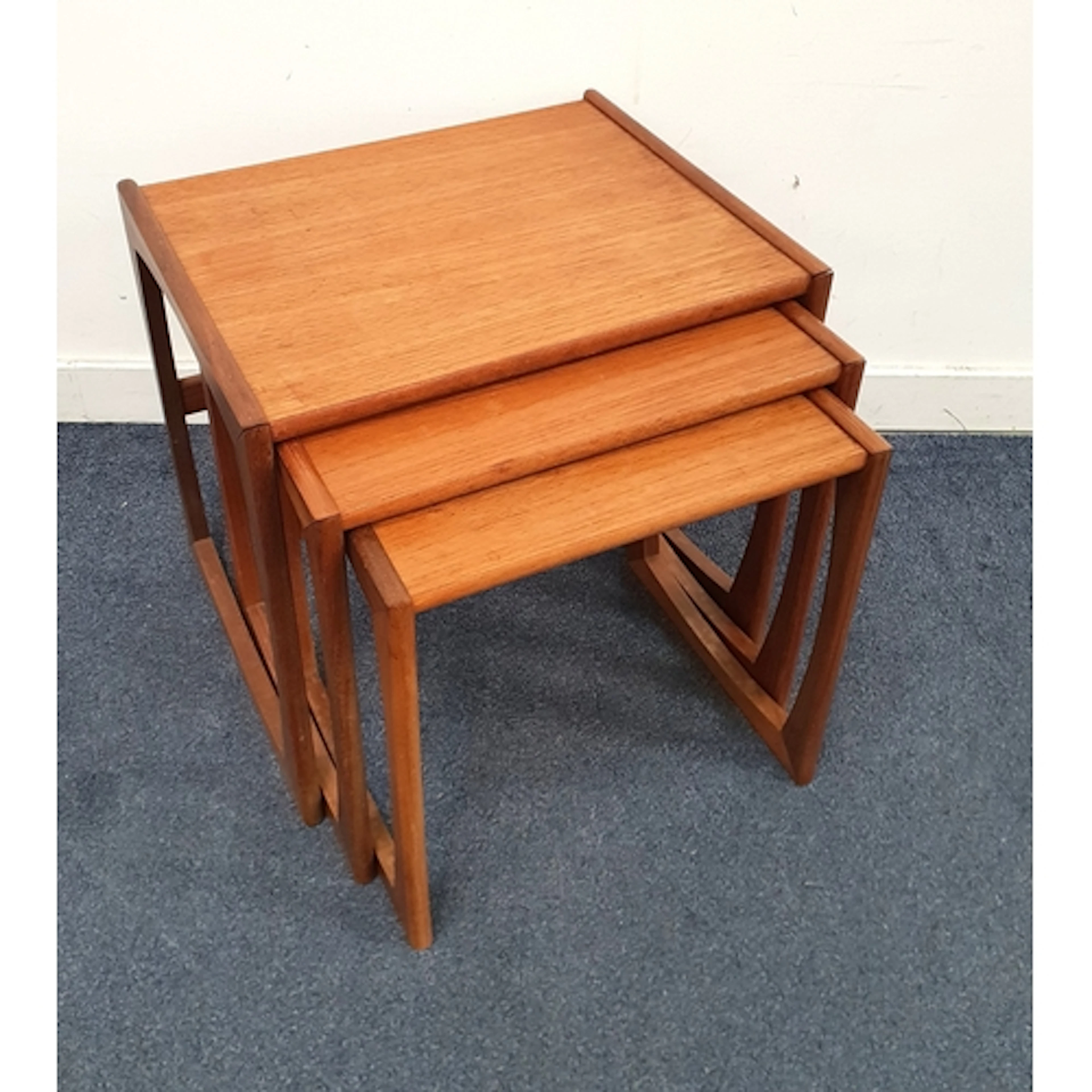 NEST OF MID CENTURY TEAK OCCASIONAL TABLES with shaped side...