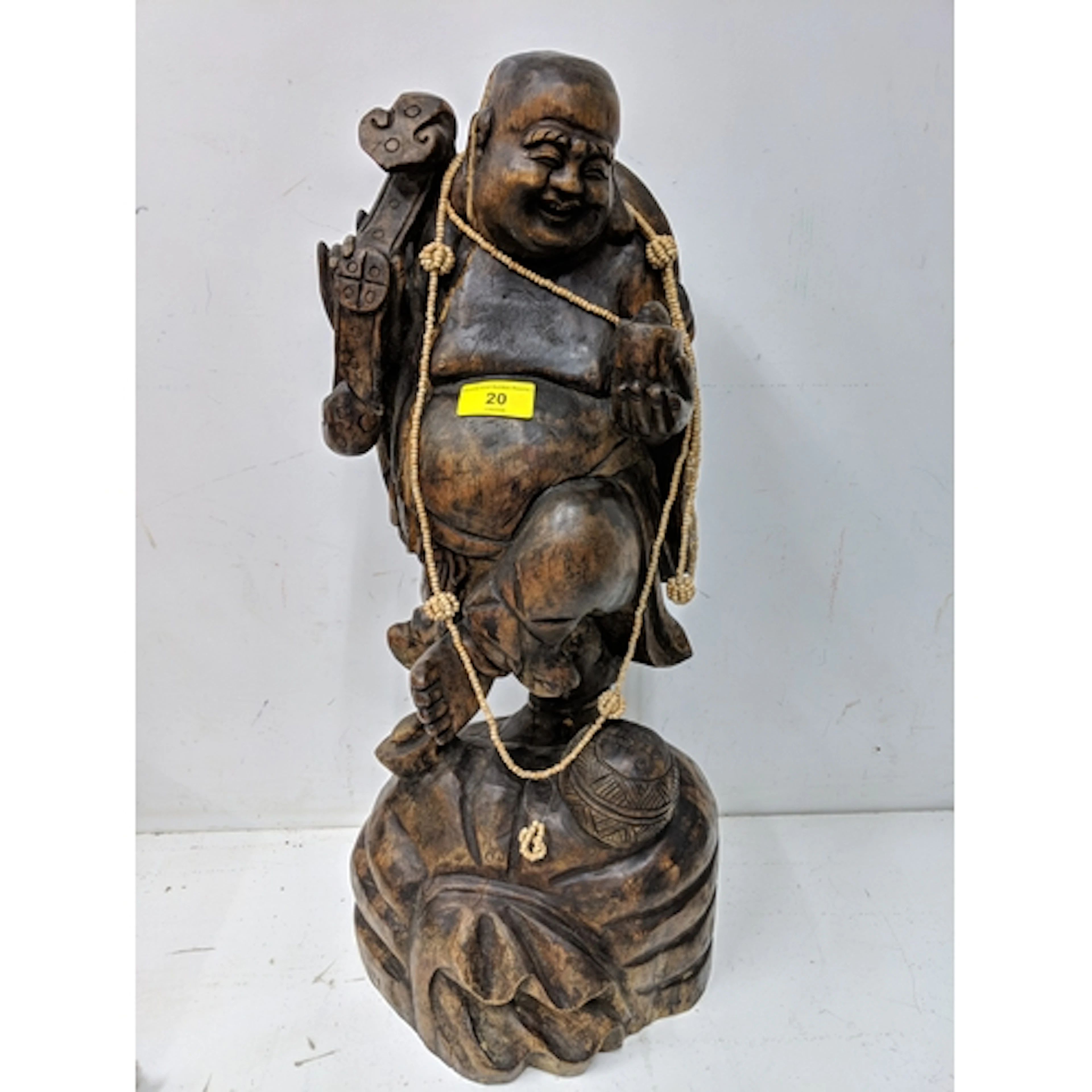 A large carved buddha with beads on a plinth 58cm H Location...