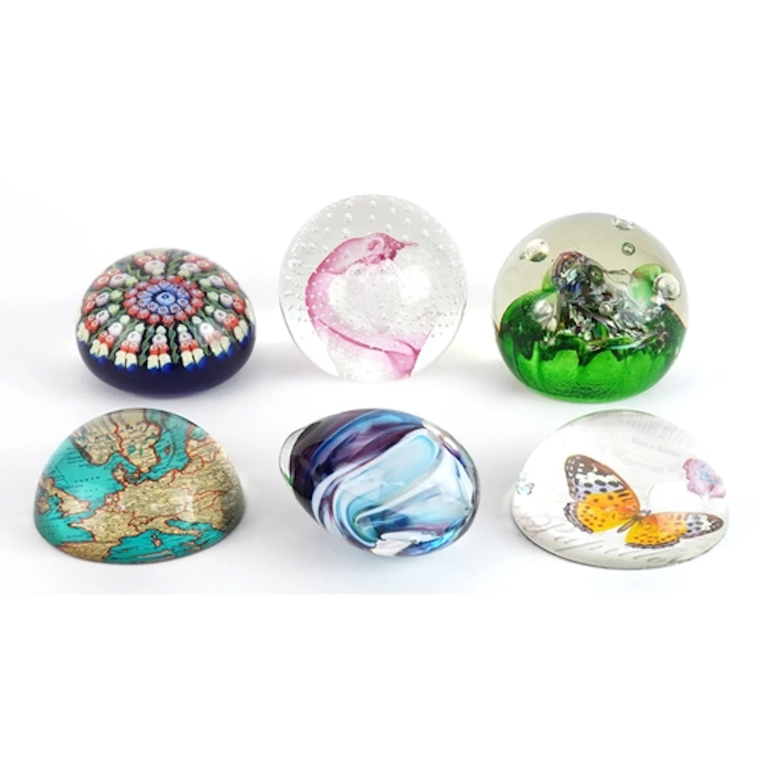 Six colourful glass and composite paperweights including one...