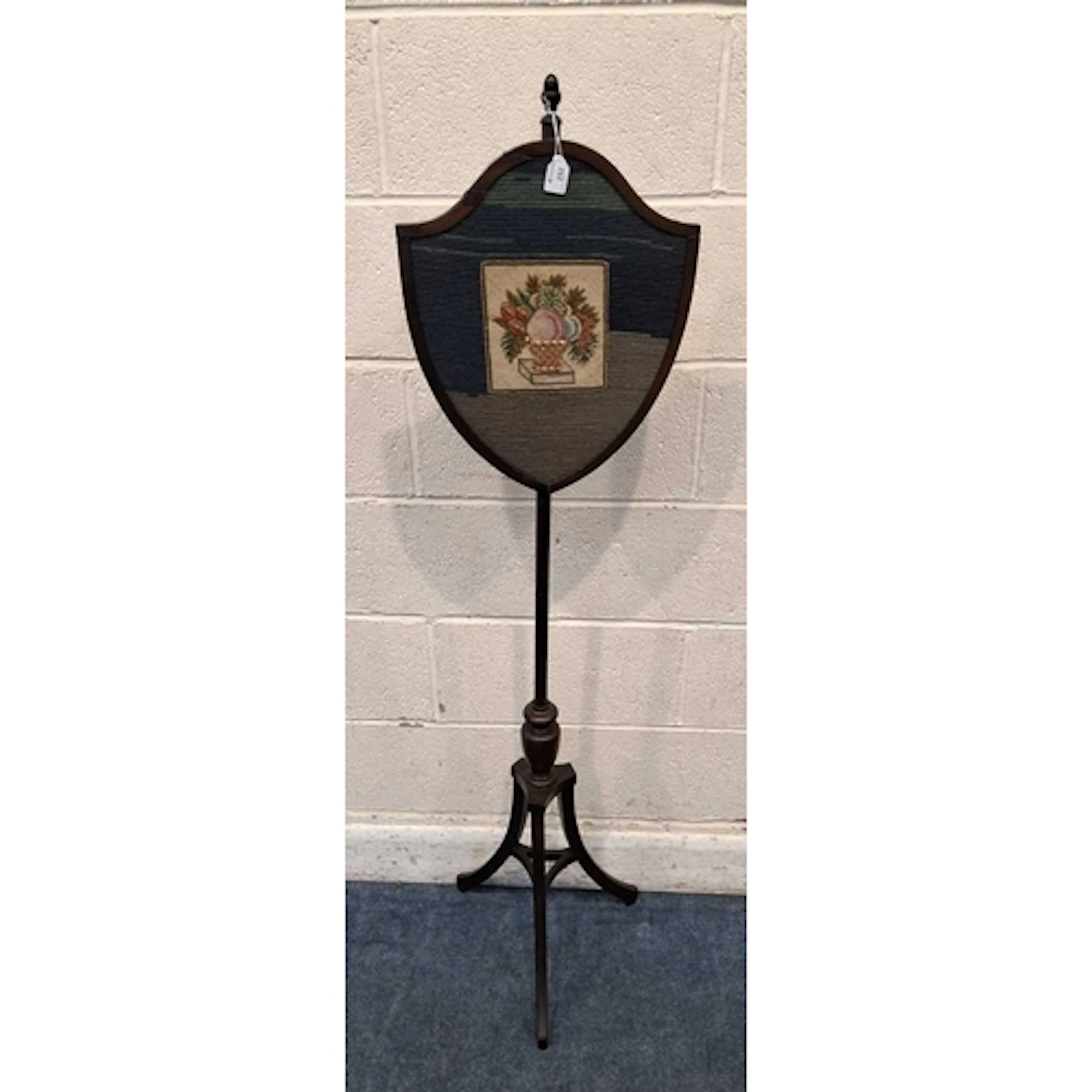 AN EDWARDIAN MAHOGANY POLE SCREEN, with a shield-shaped tape...