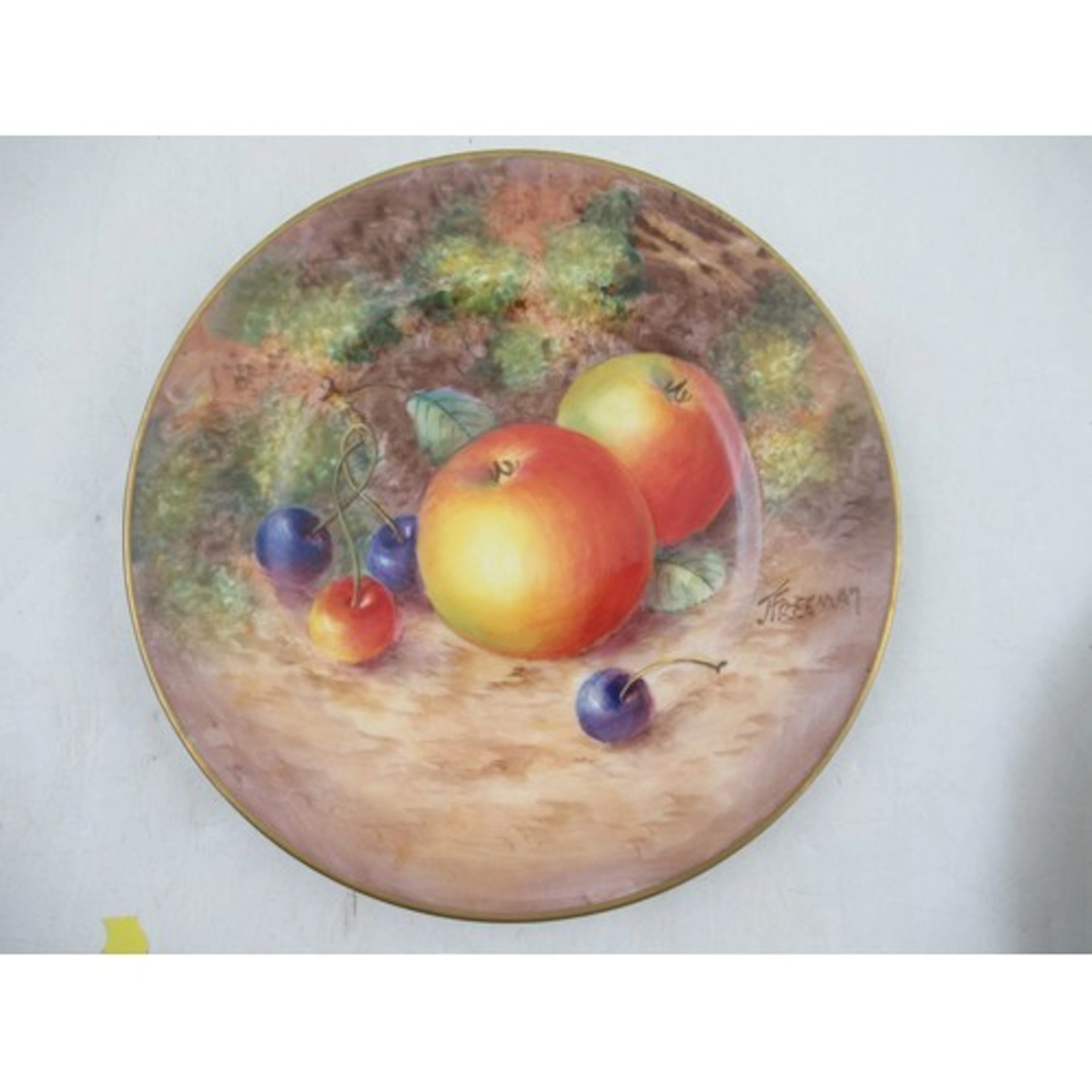 A Royal Worcester side plate, decorated with fruit to a moss...