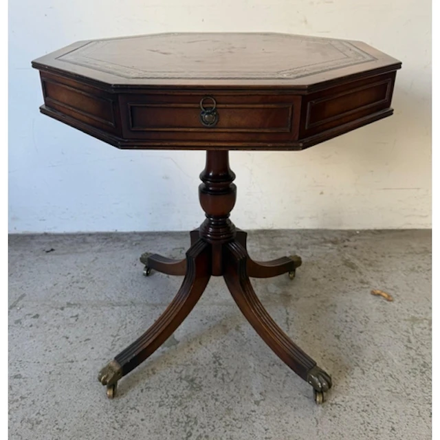A hexagonal red leather topped drum table with four opening ...