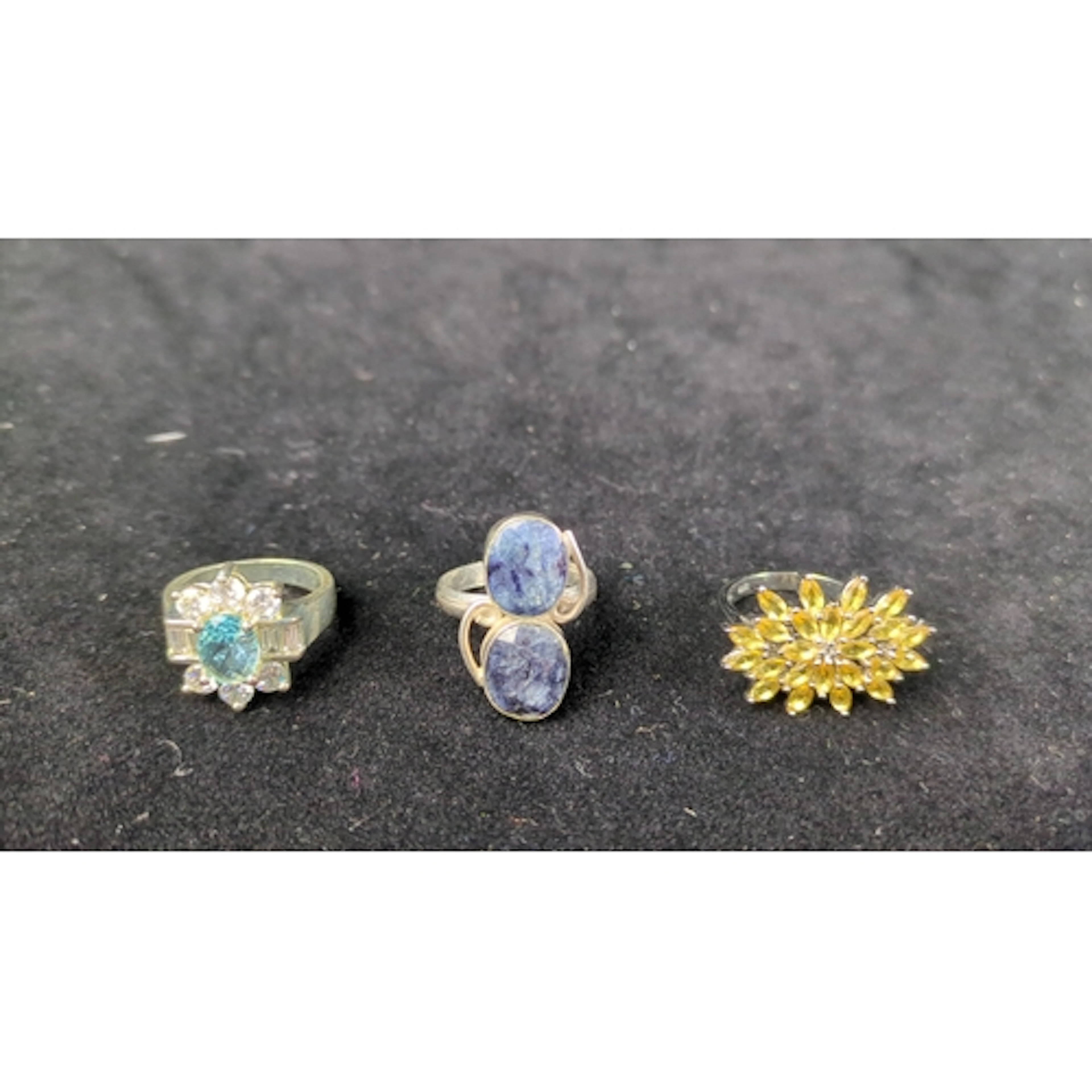 Three silver rings: one with an oval blue-green stone and co...