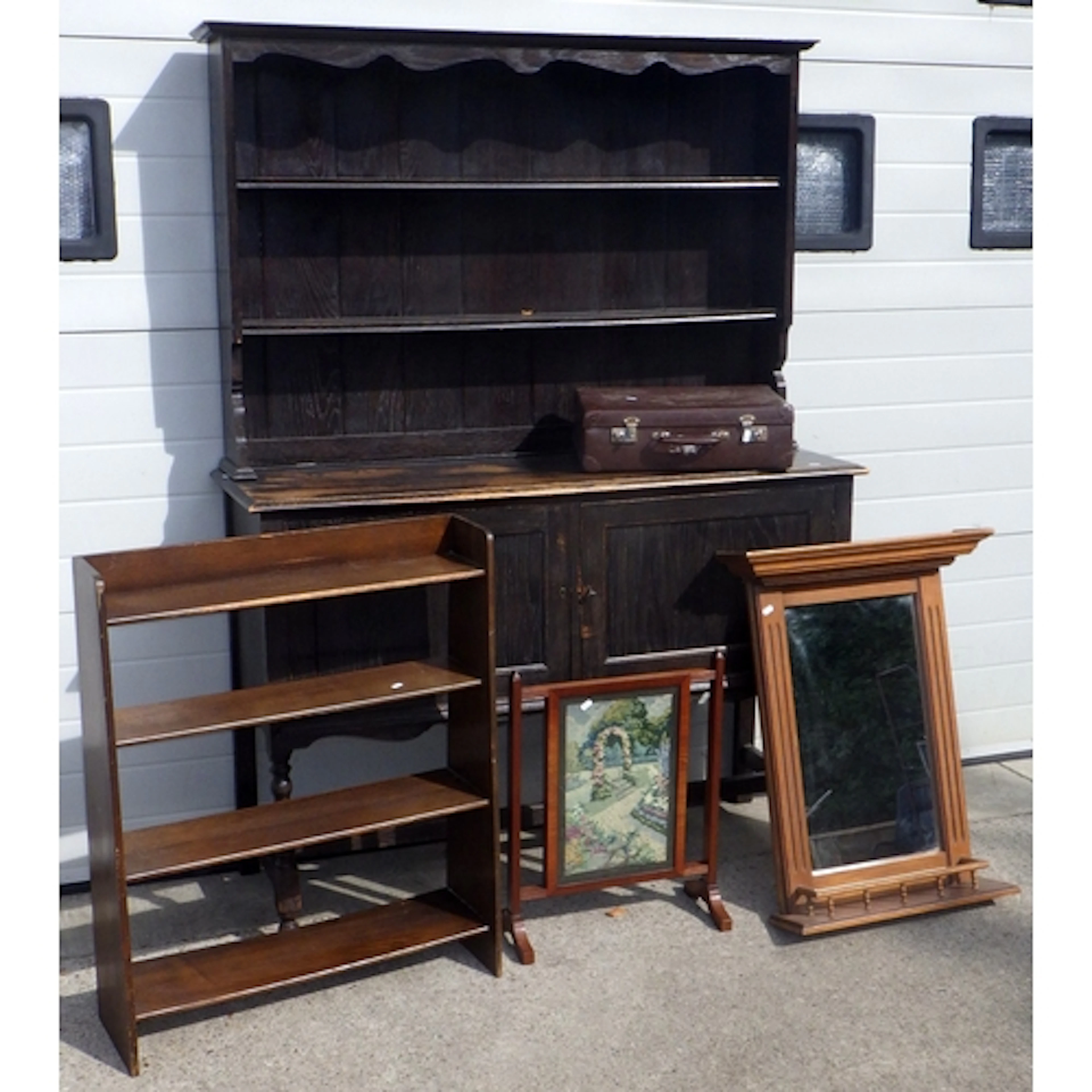 A dark stained dresser, open bookcase, two suitcases, mirror...