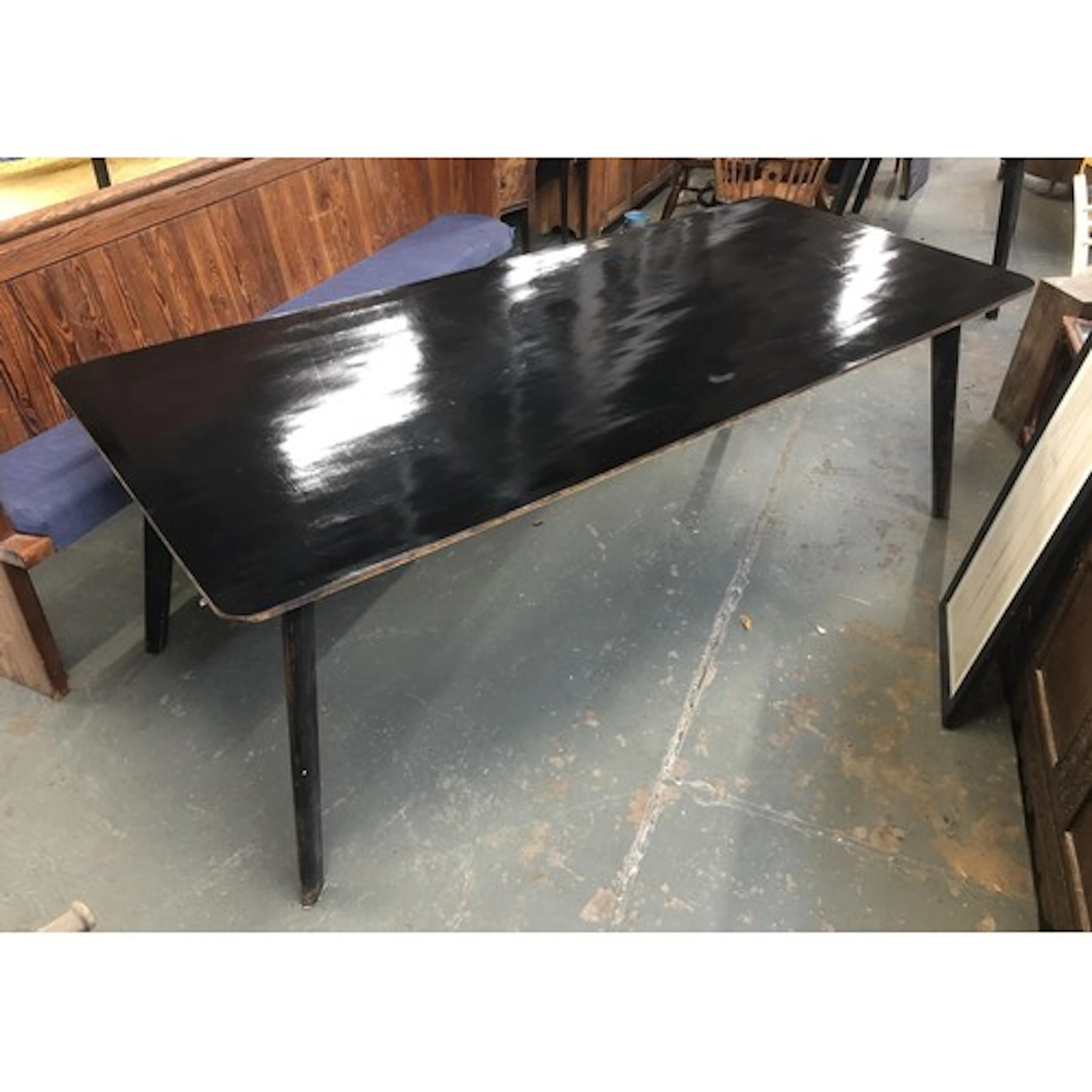 A mid century black formica topped kitchen table, on splayed...
