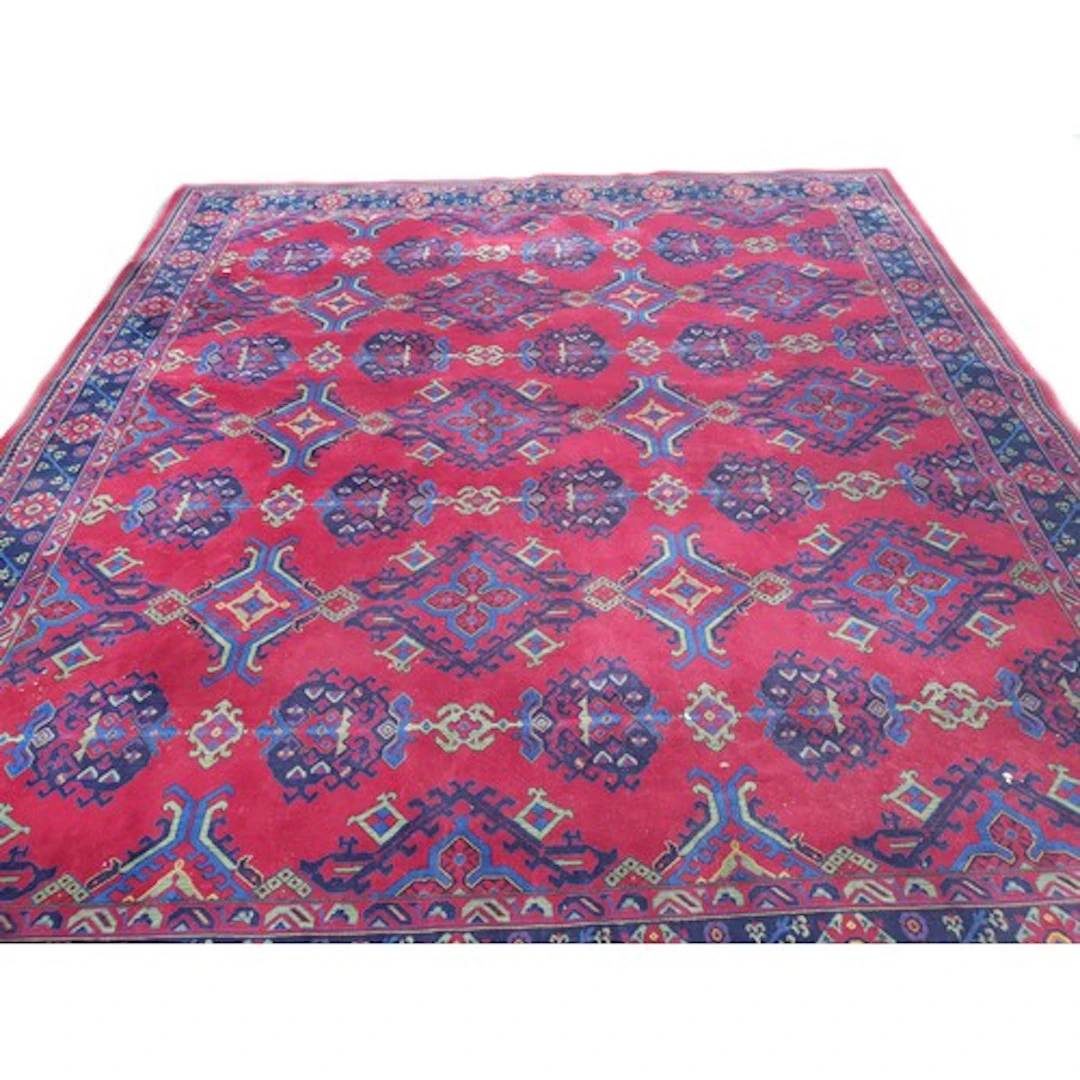 LARGE BRINTONS HAND KNOTTED WOOL RUG with a crimson-red fiel...