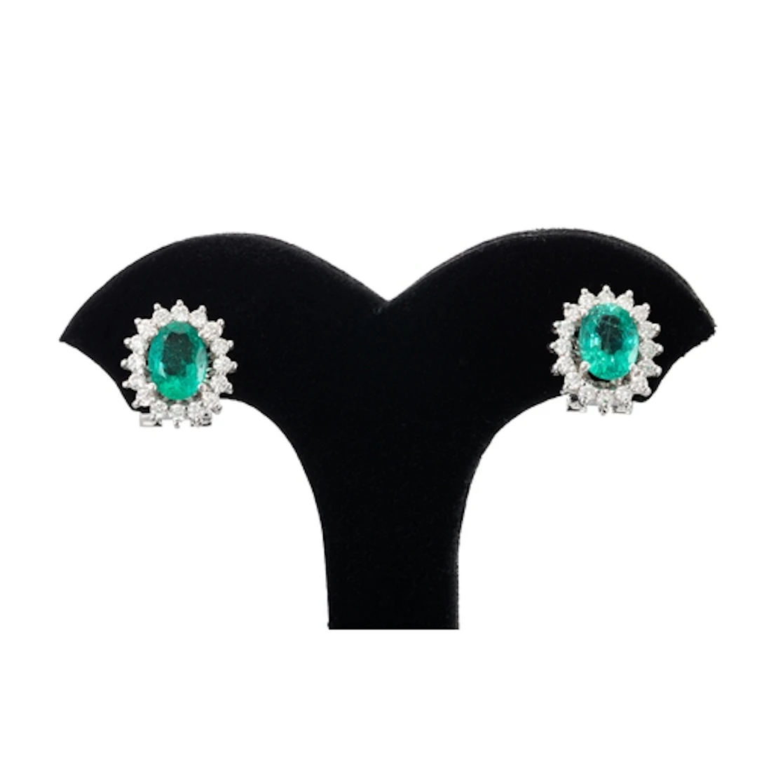 A PAIR OF EMERALD AND DIAMOND CLUSTER EARRINGS, the oval eme...