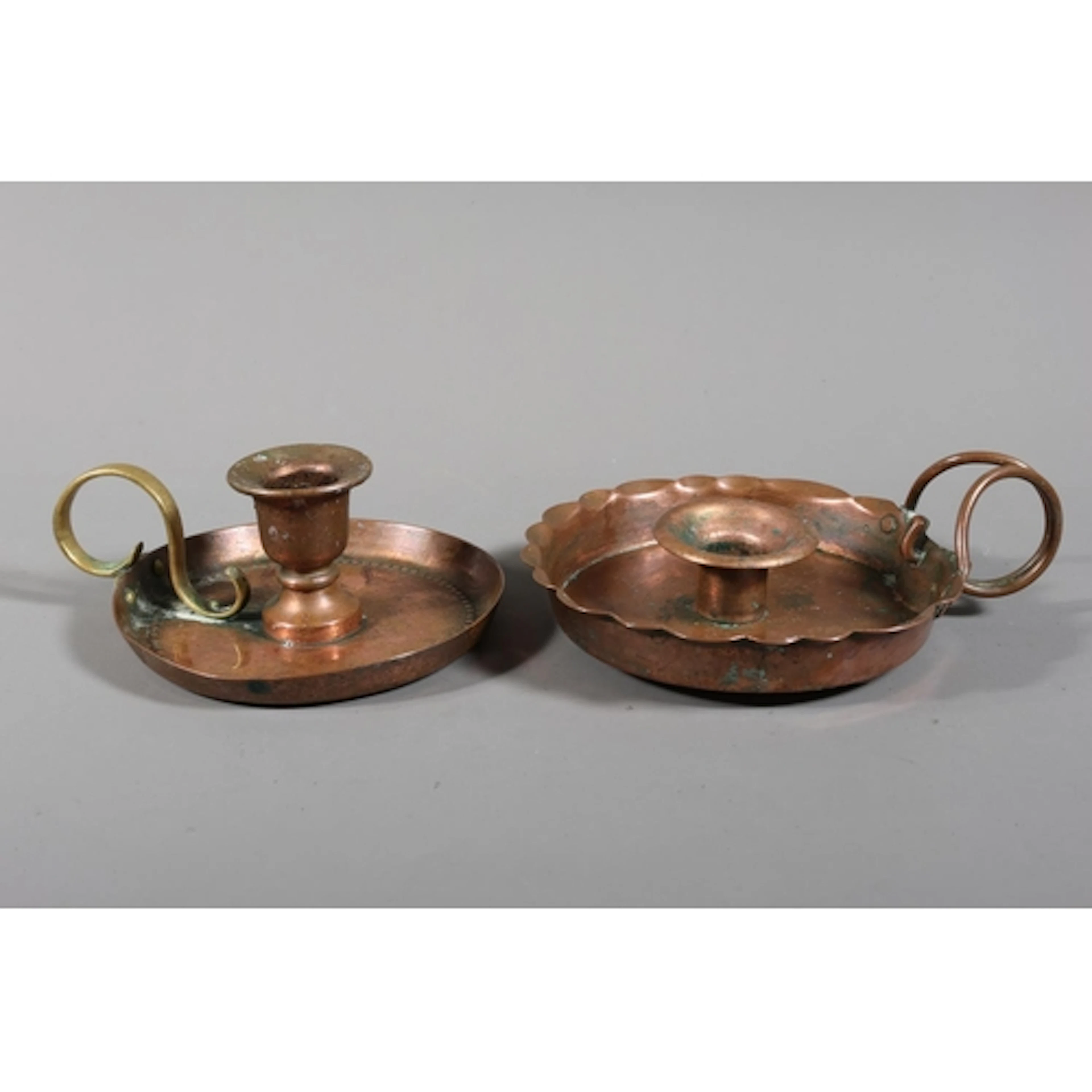 Two copper Arts & Crafts candle holders with drip trays,...