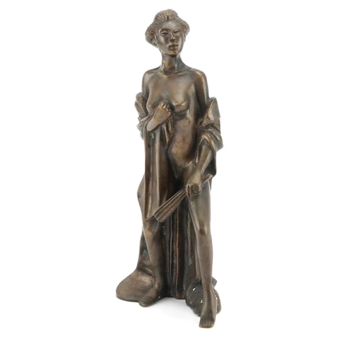 A bronzed spelter figure of a nude Asian female in a robe an...