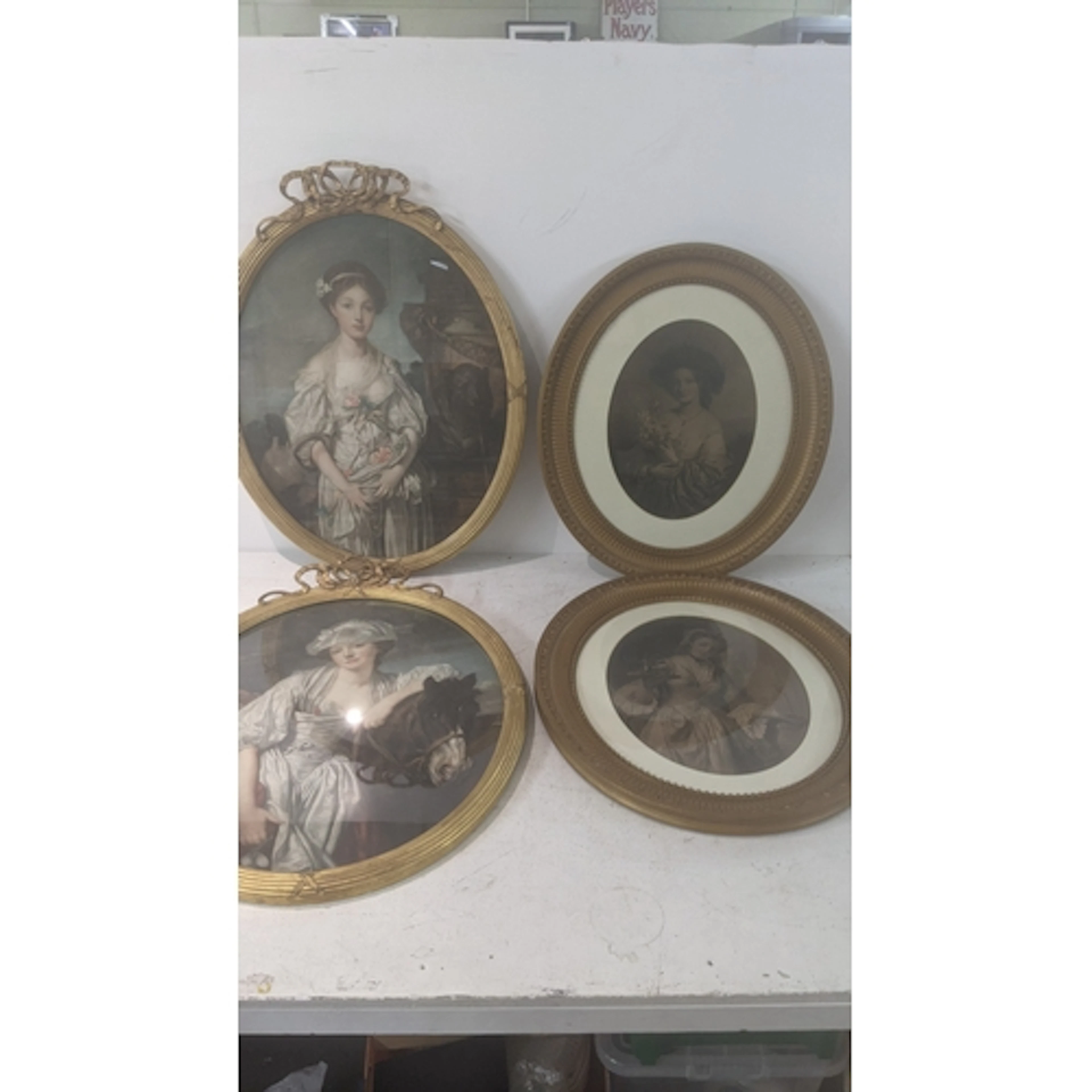 A group of four oval framed prints depicting young ladies in...