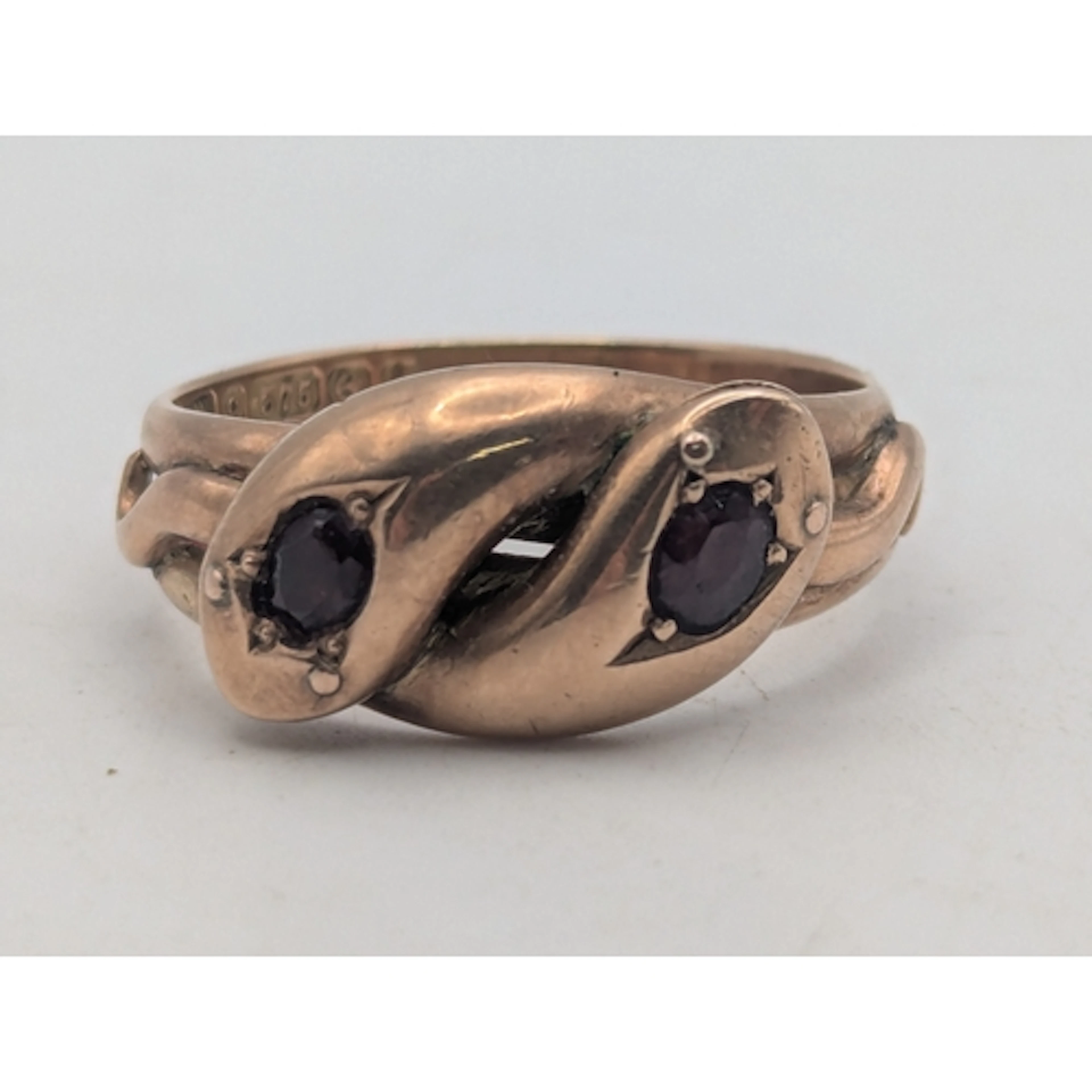 An Edwardian 9ct rose gold and garnet snake ring featuring e...