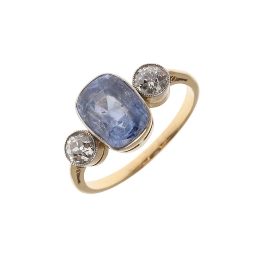 A SAPPHIRE AND DIAMOND THREE STONE RING. the rounded rectang...
