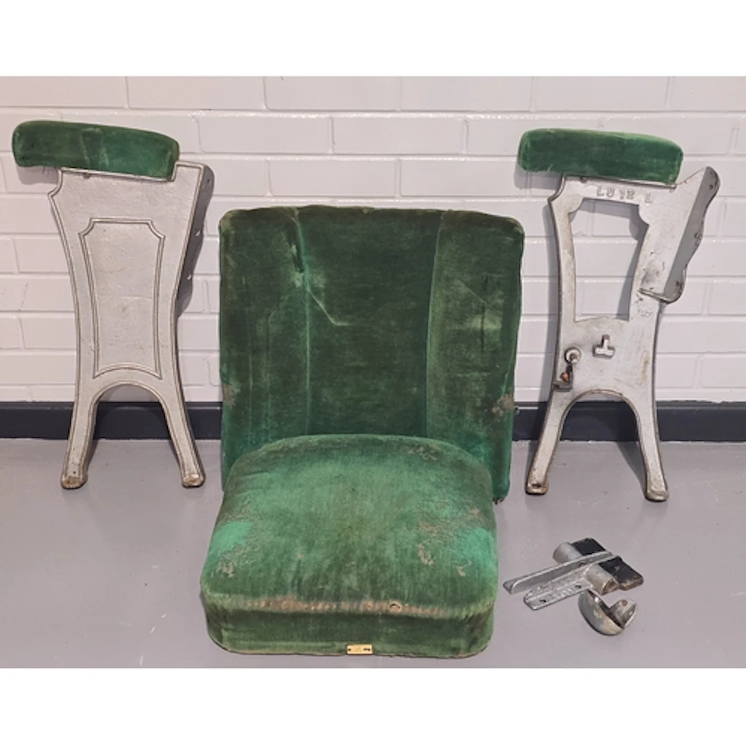 A vintage mid 20th century green velvet cinema seat with cas...