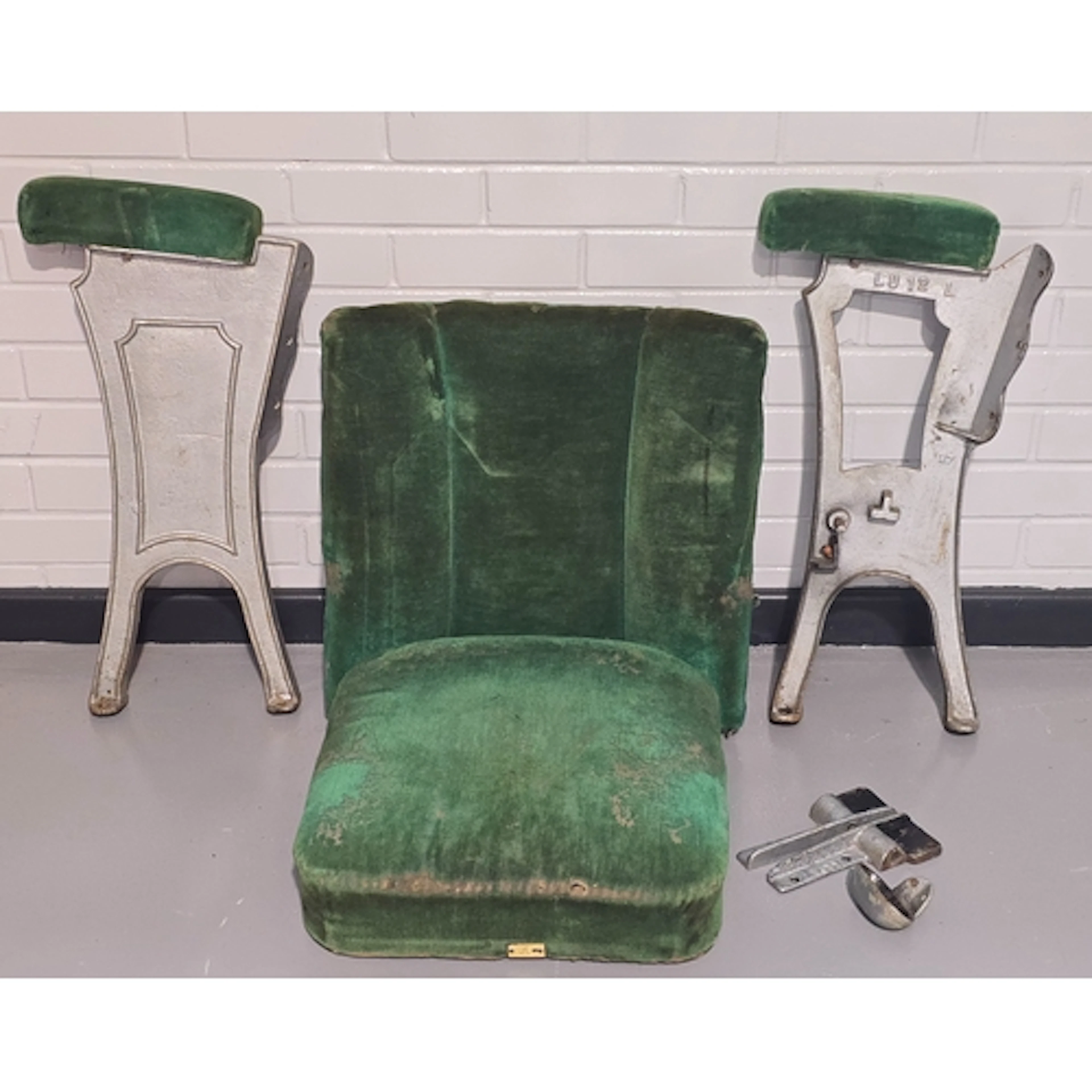 A vintage mid 20th century green velvet cinema seat with cas...