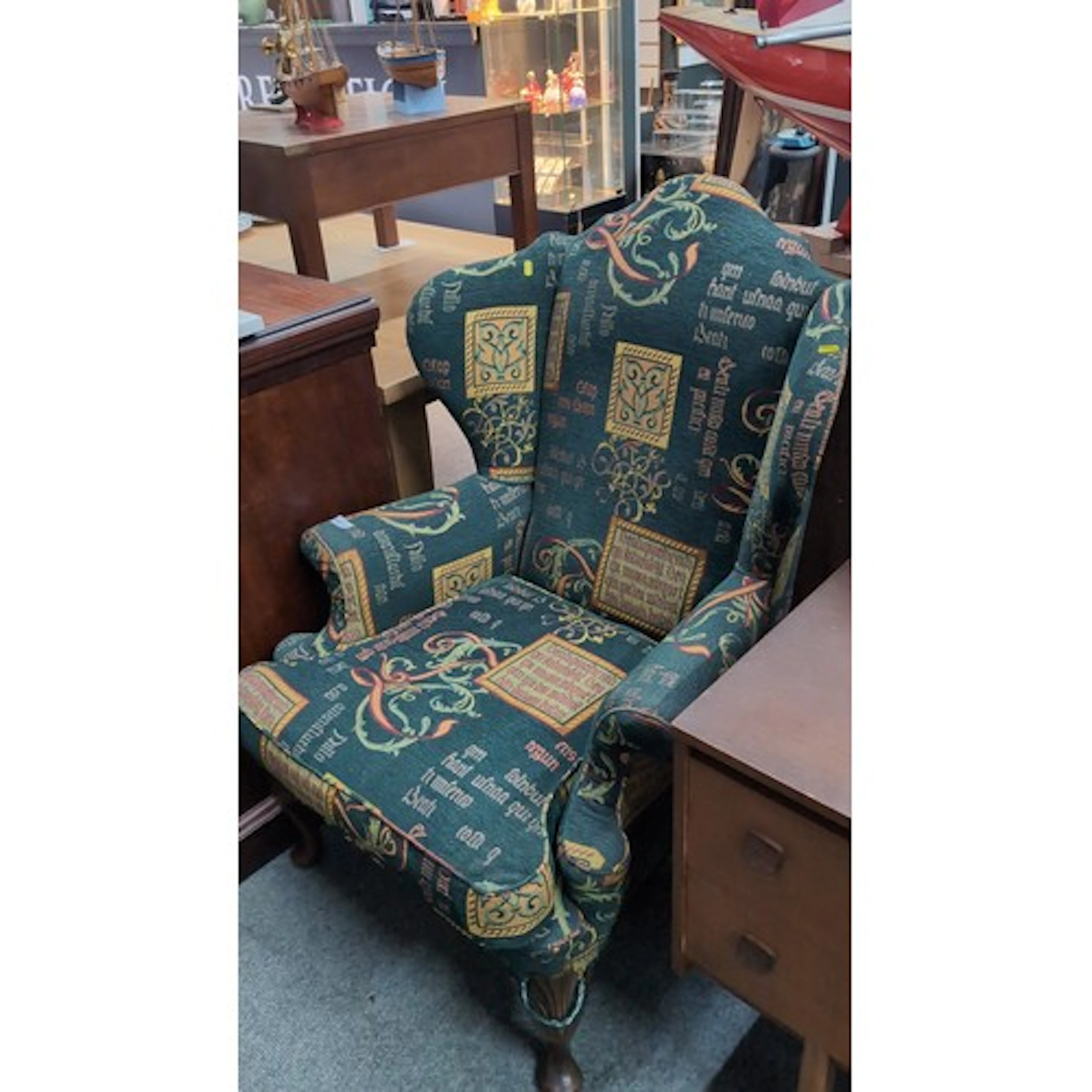 Upholstered wingback armchair with camelback cresting and sc...