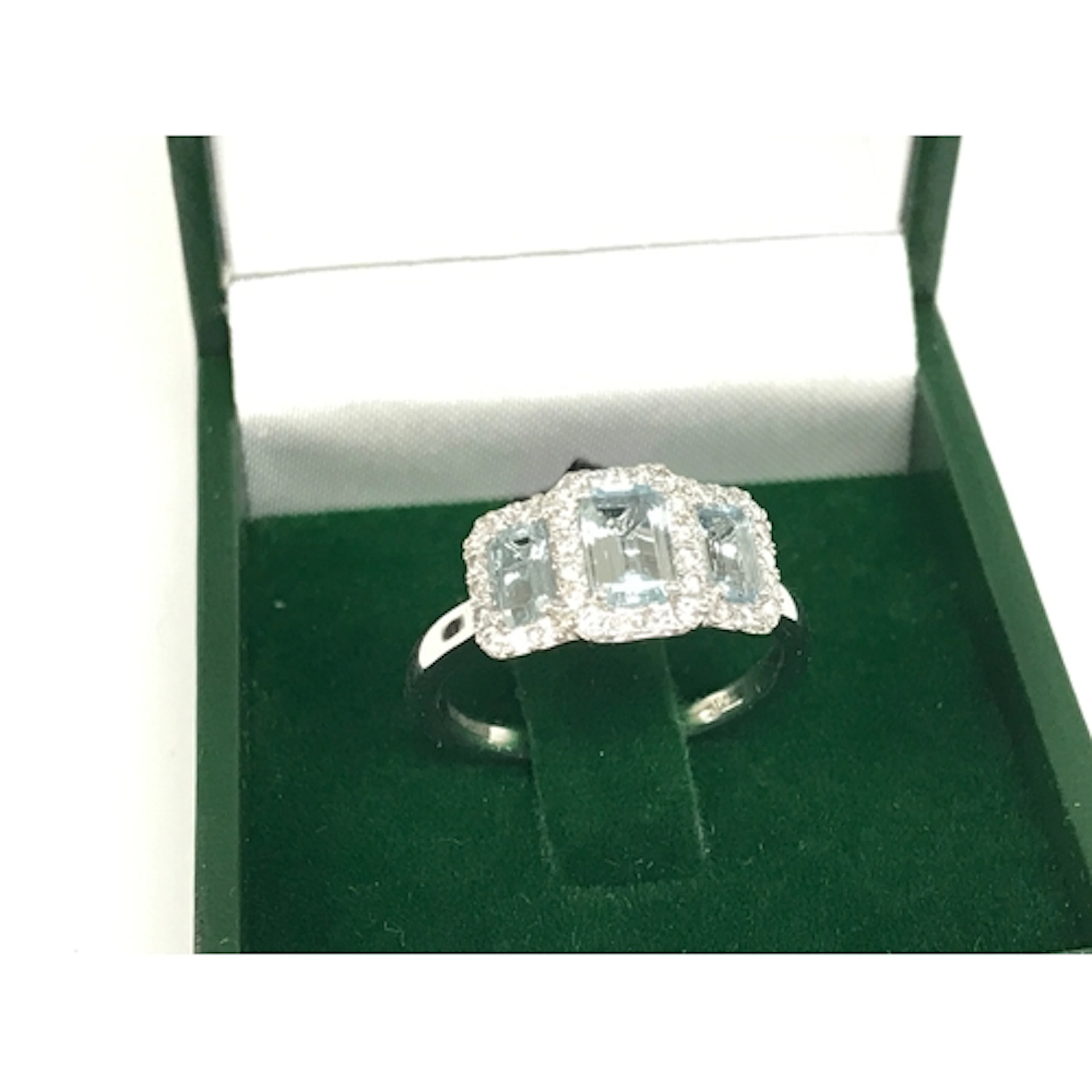 A platinum step cut aquamarine and round cut diamond trilogy...