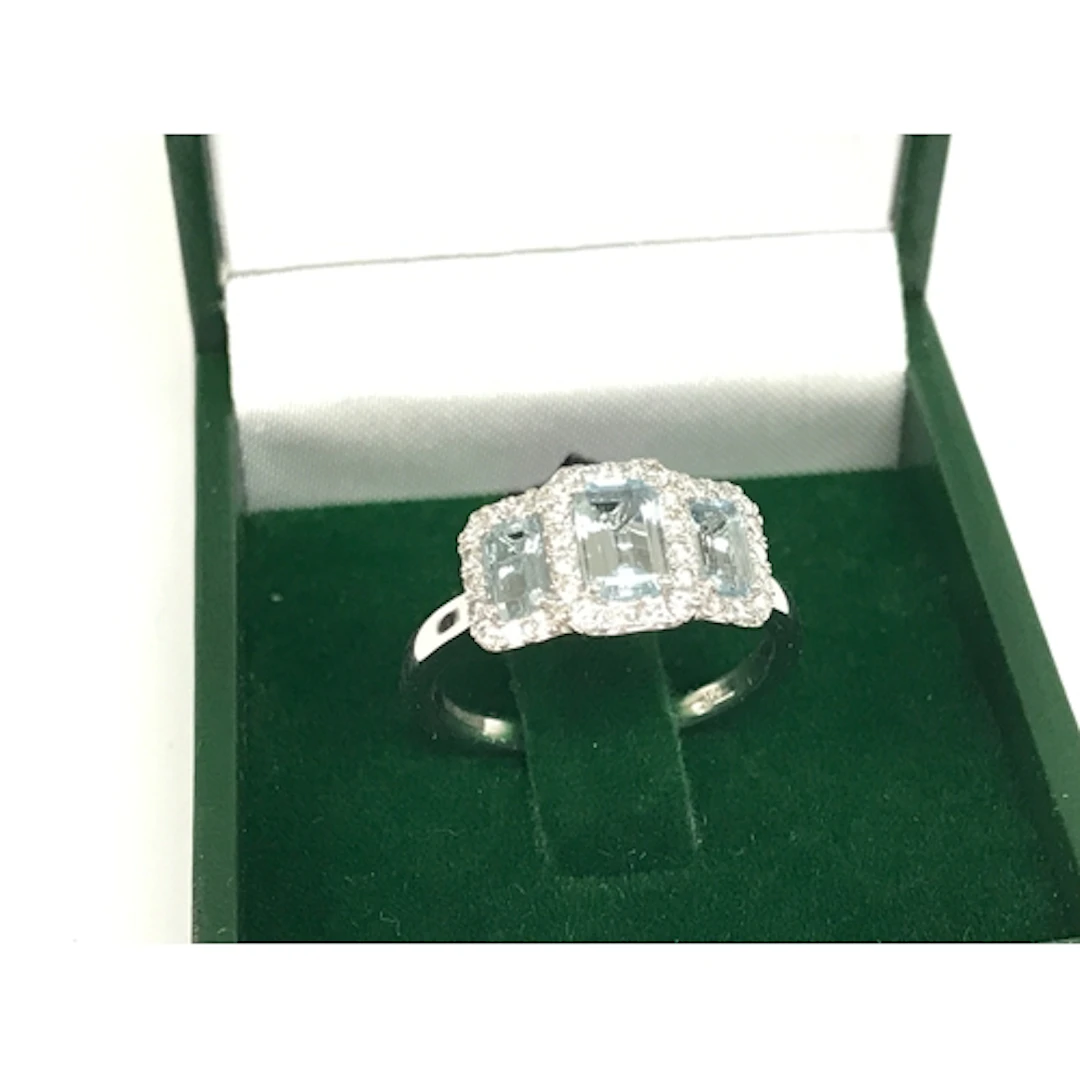 A platinum step cut aquamarine and round cut diamond trilogy...