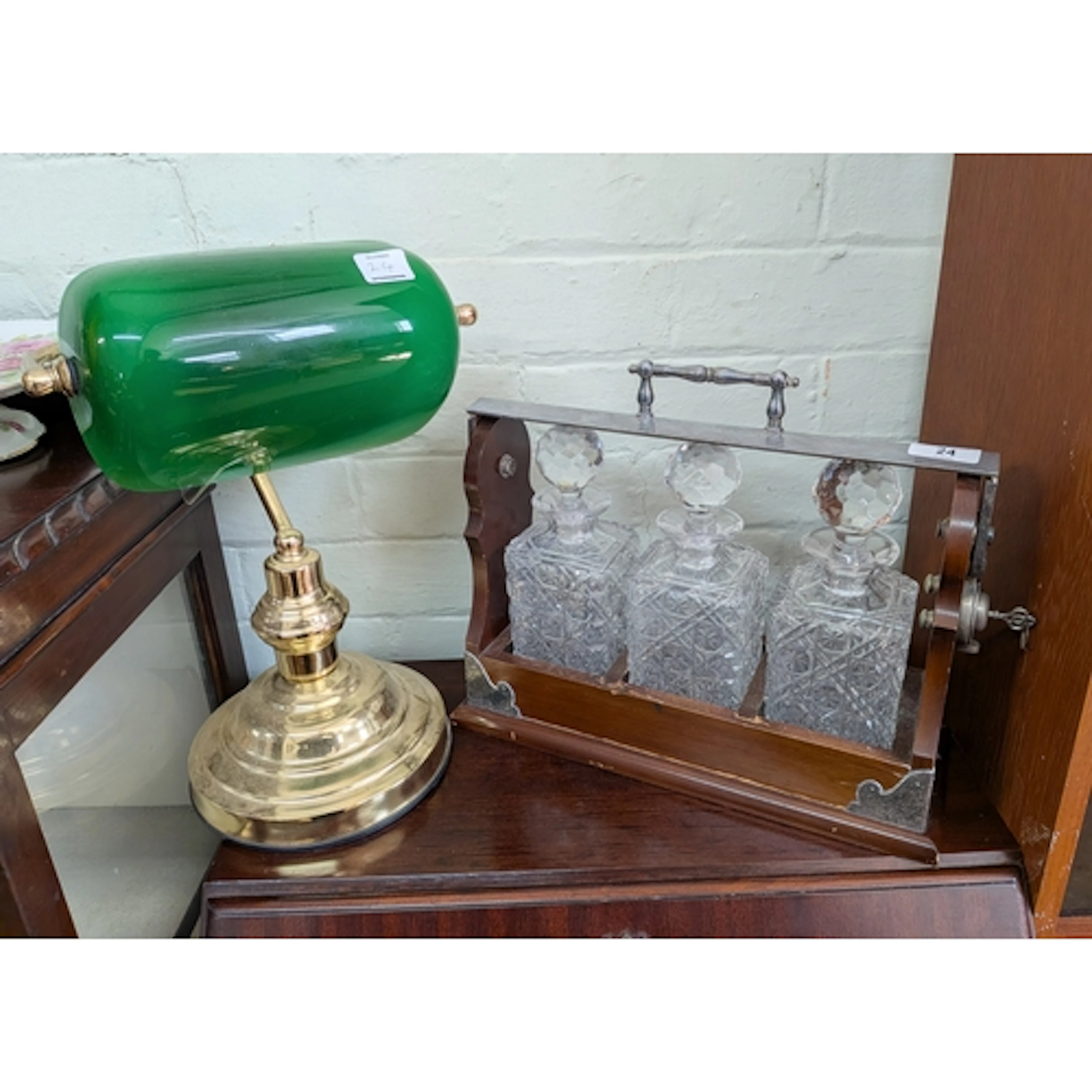 A three bottle spirit tantalus and a brass and green glass b...