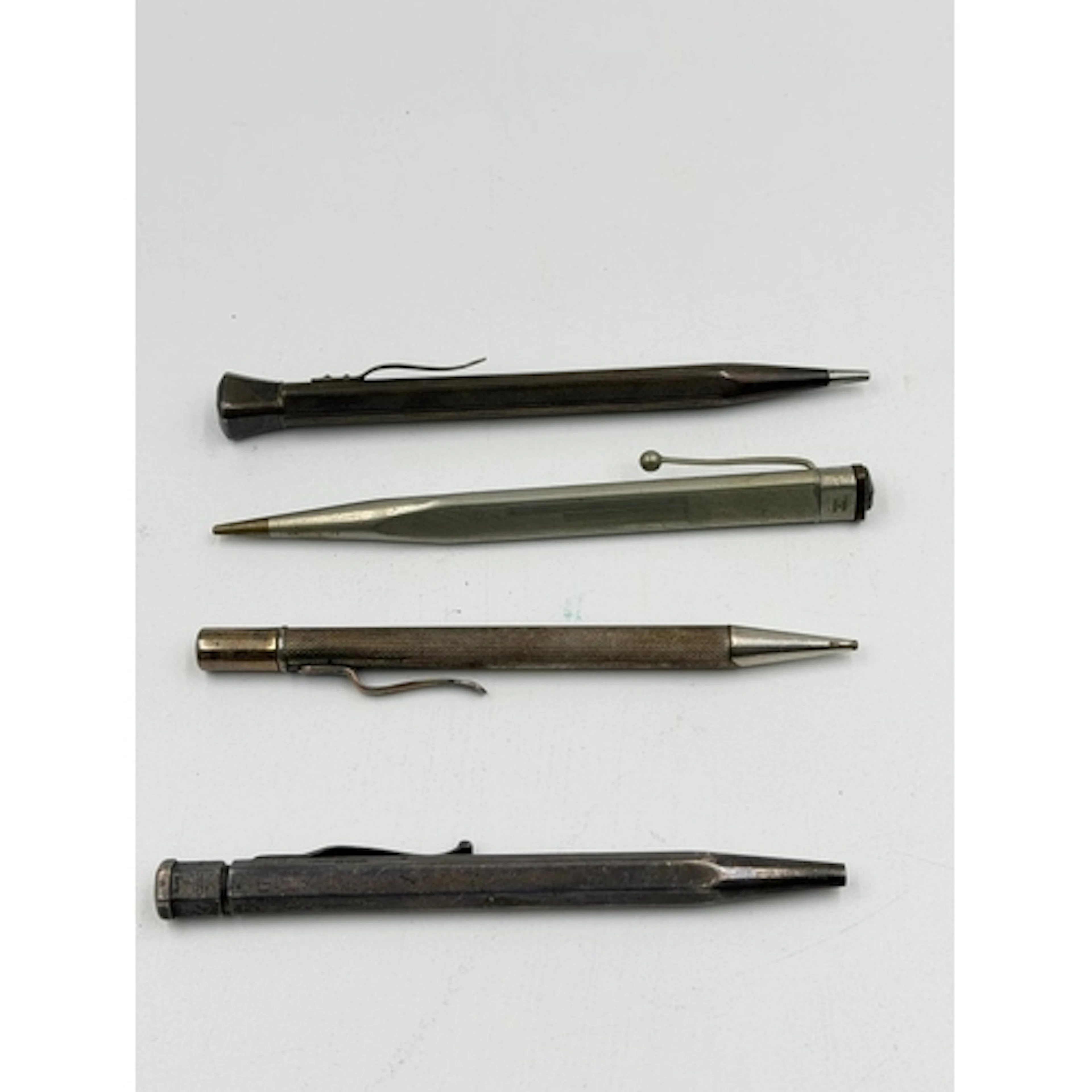 A selection of four white metal and silver rotating pencils...