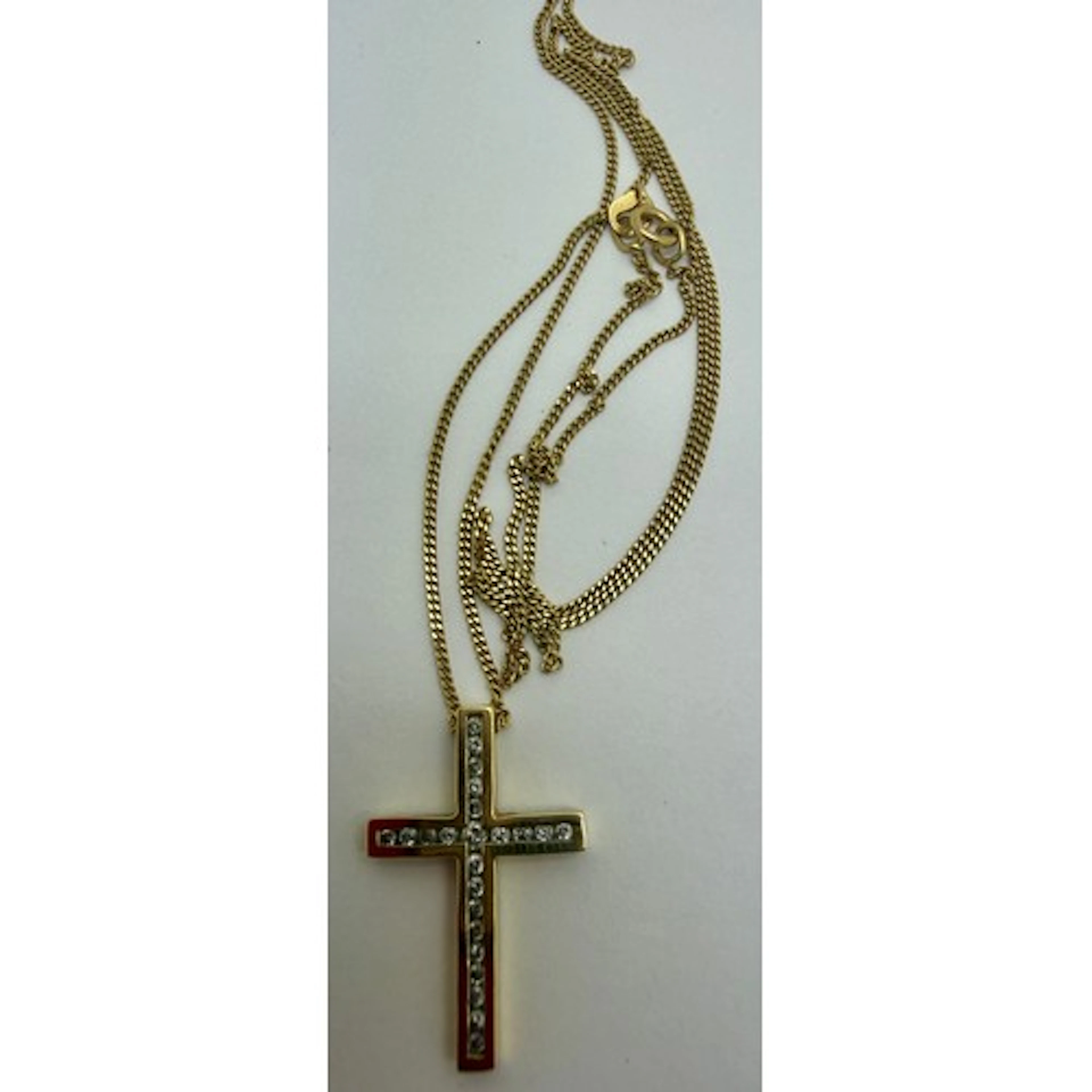 An 18 carat gold crucifix set with clear stones on an 18 car...