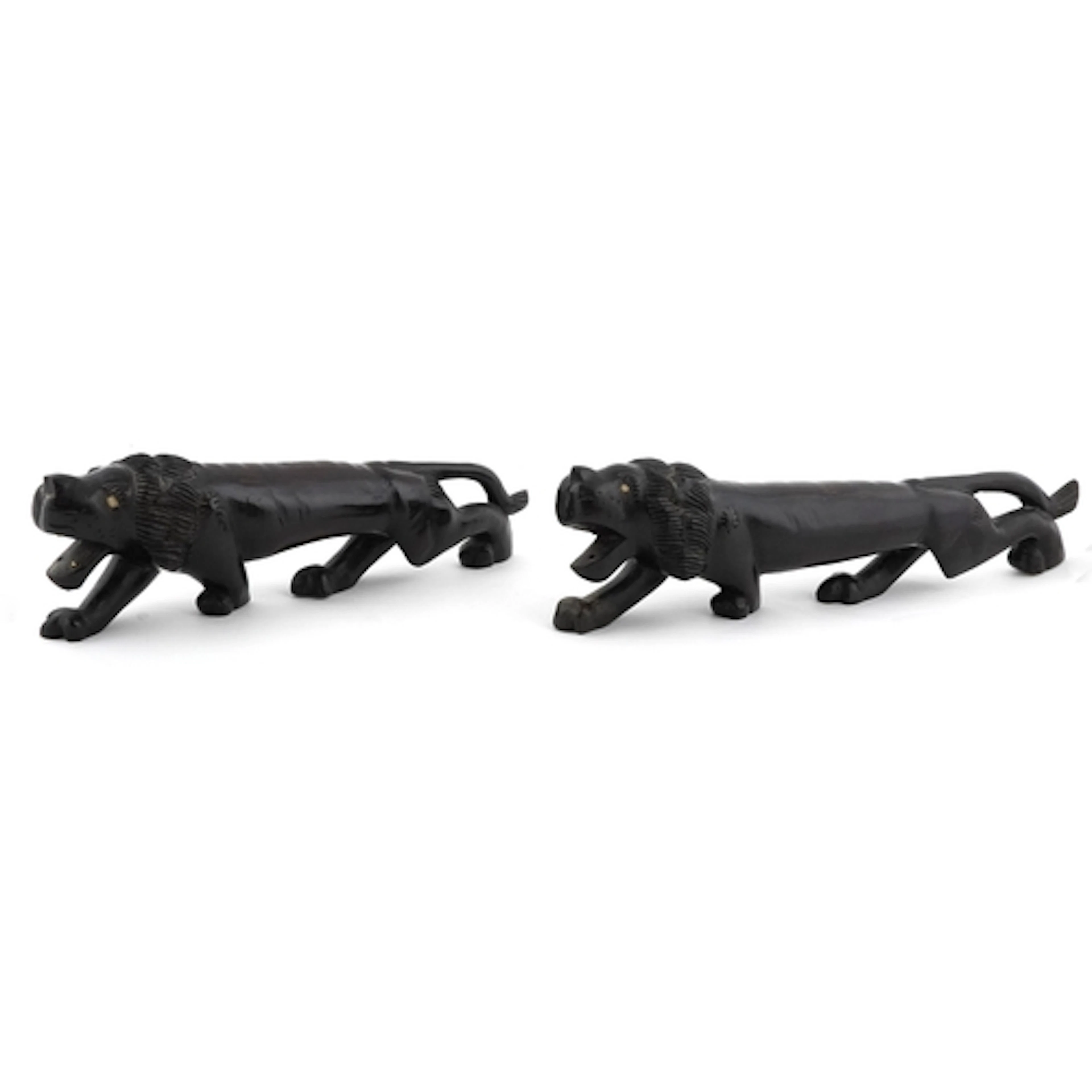 Two large wooden hand carved crouching African lions, the la...