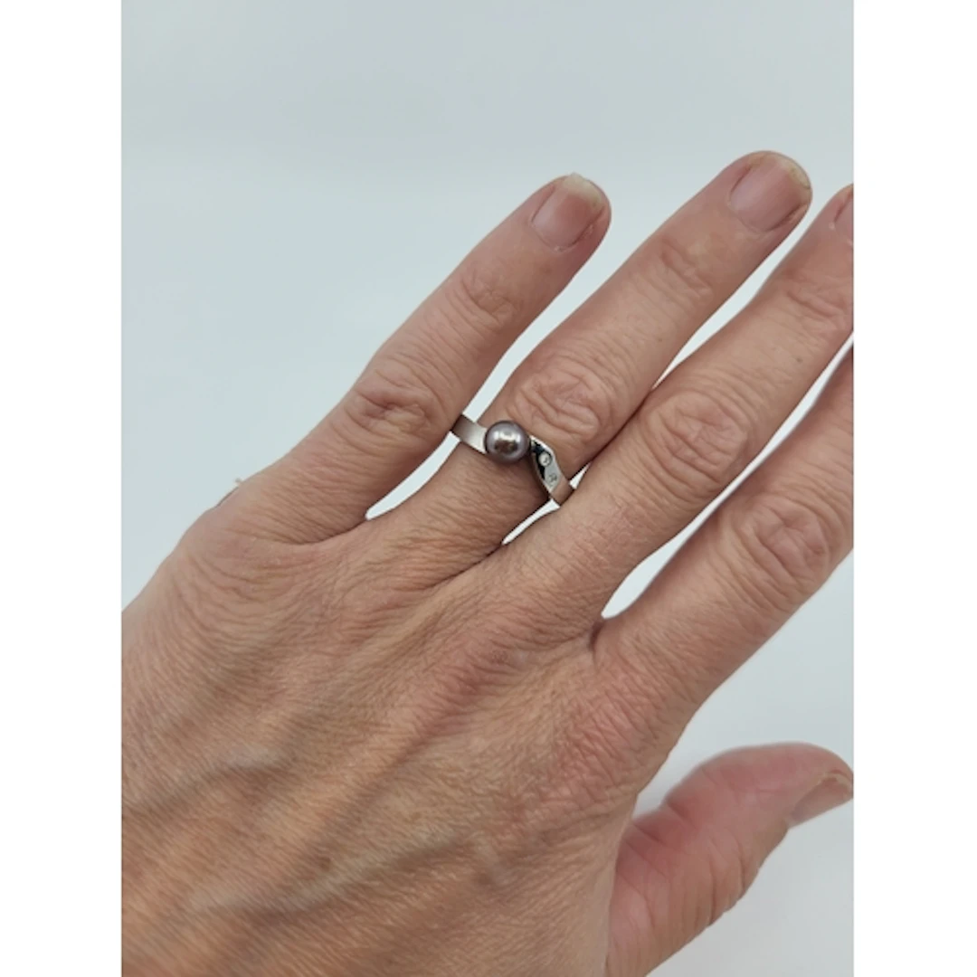 A CULTURED PEARL AND DIAMOND SET RING, grey tones of twist d...