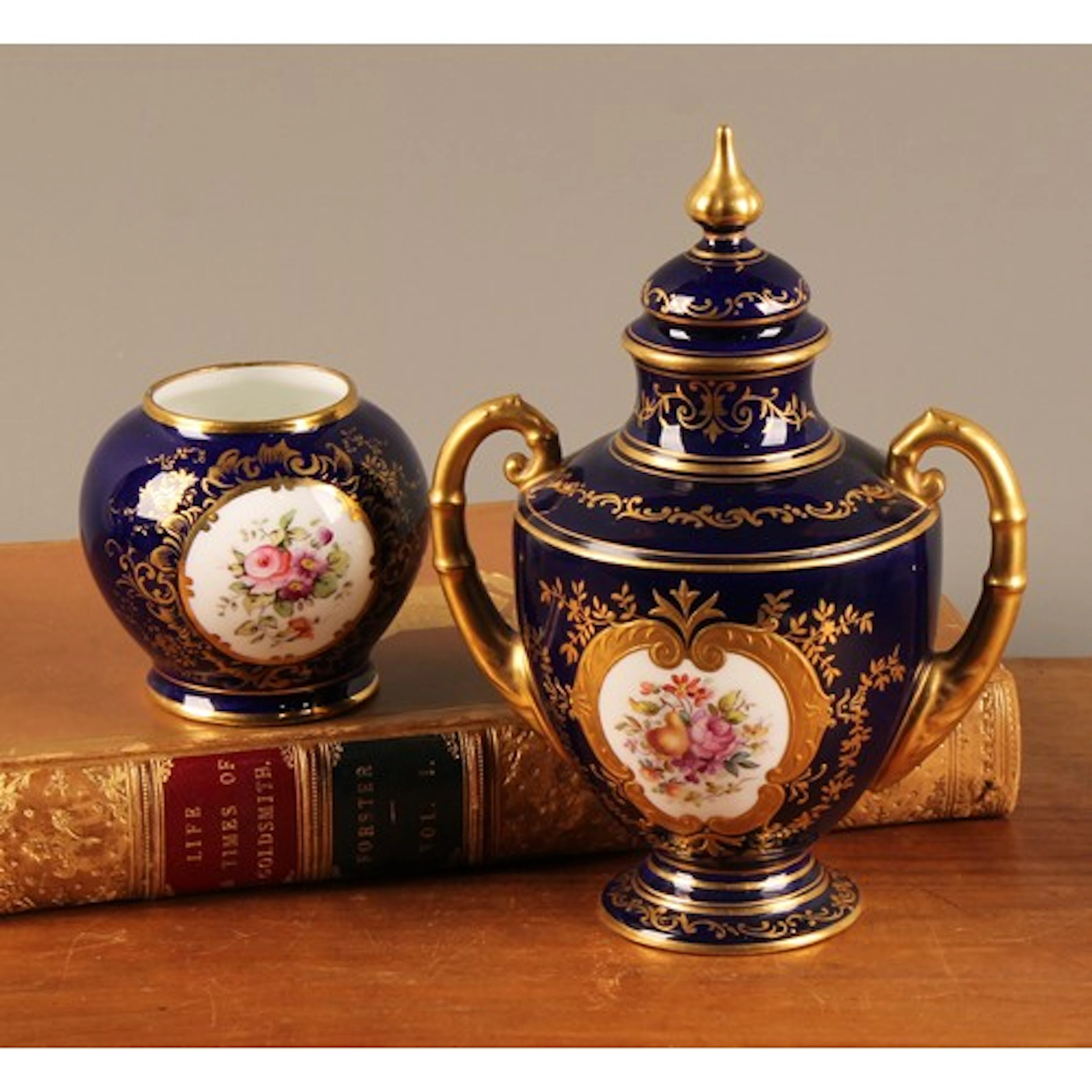 A Coalport two handled pedestal vase and cover, painted with...