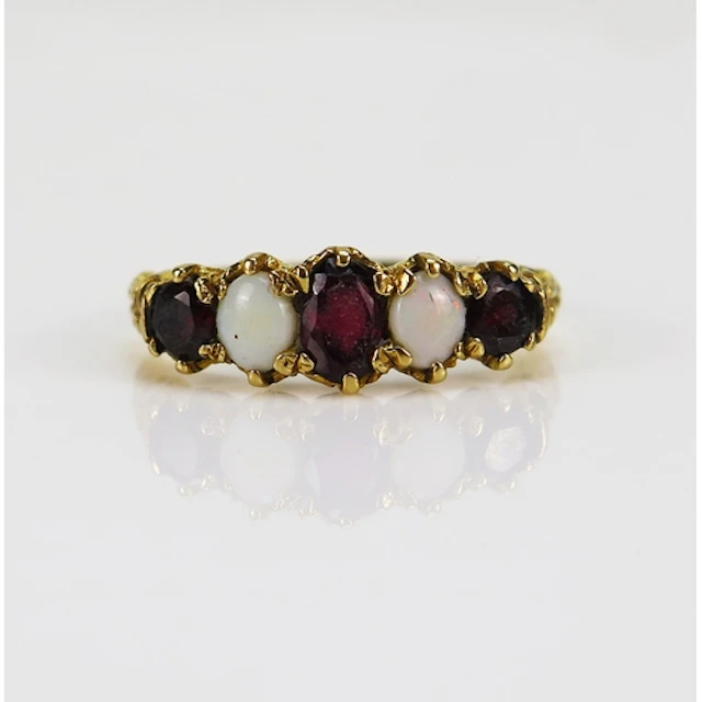 An opal and garnet ring in a 9ct yellow gold setting, size S...