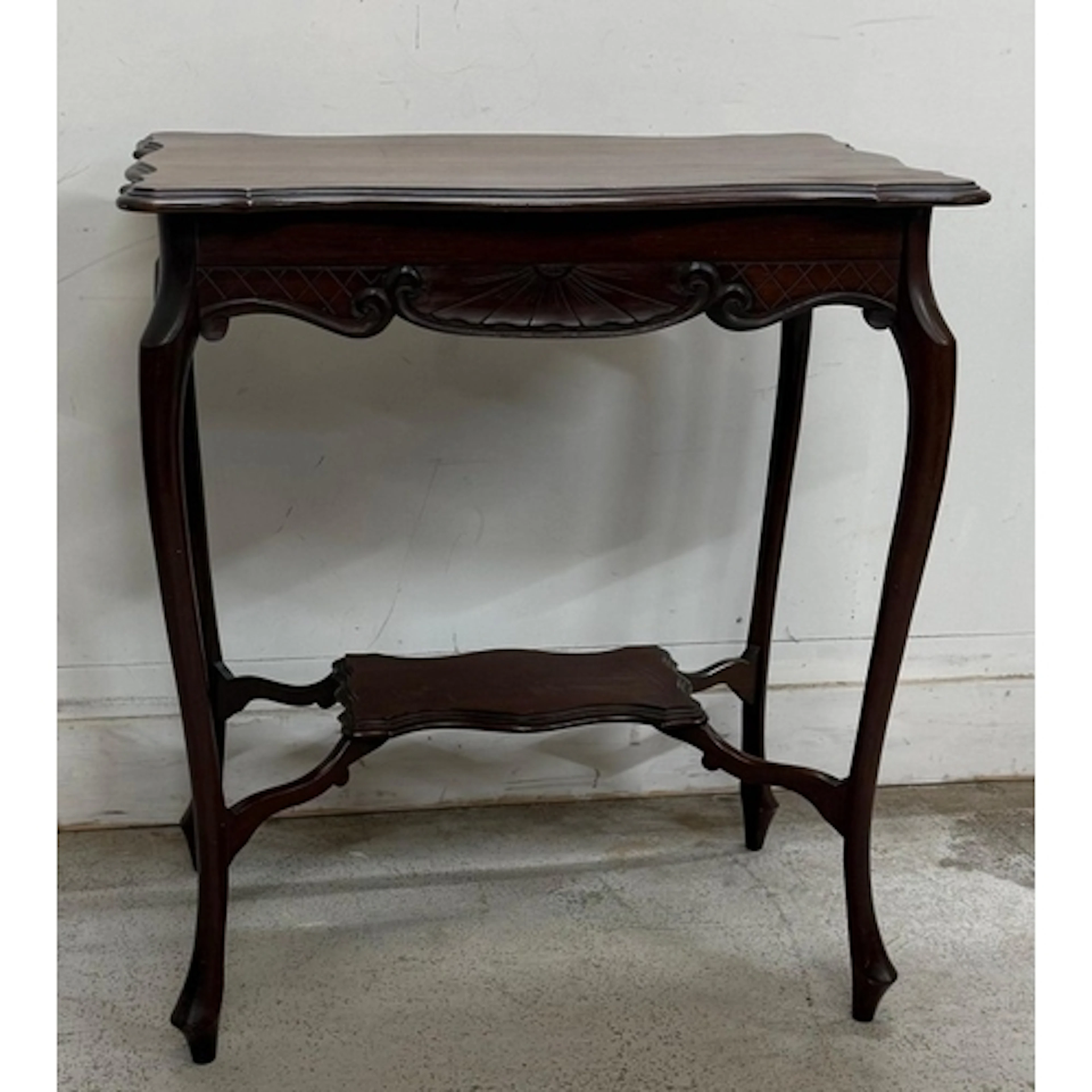 A mahogany two tier occasional table with scalloped top and ...