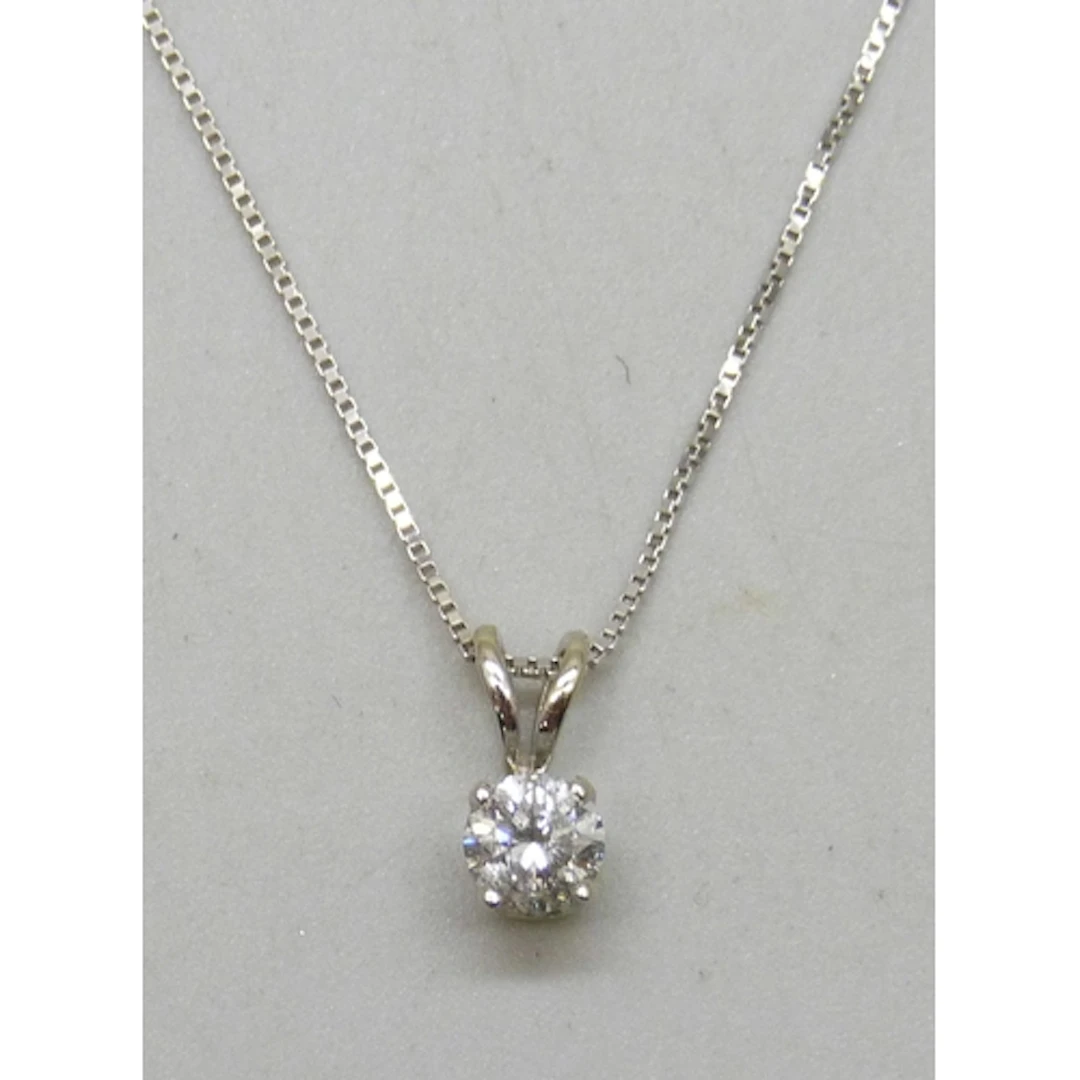 A 14k white gold diamond solitaire pendant, on a 10k white g...