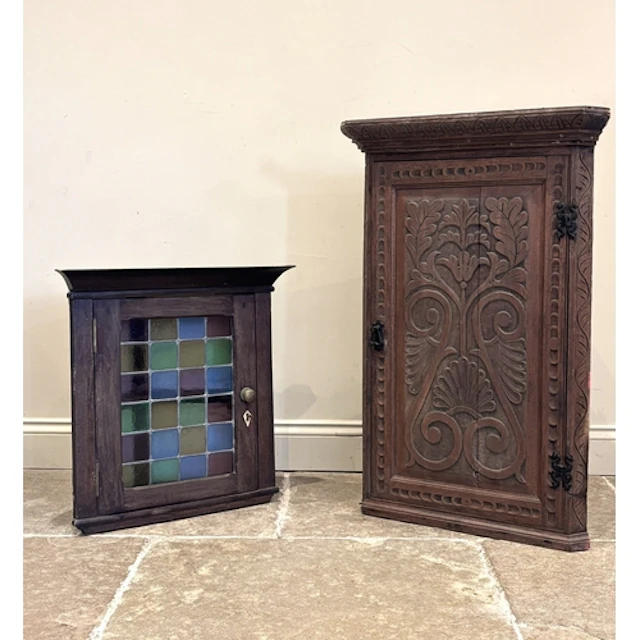 A 17th century style carved oak corner cupboard, the wall ha...
