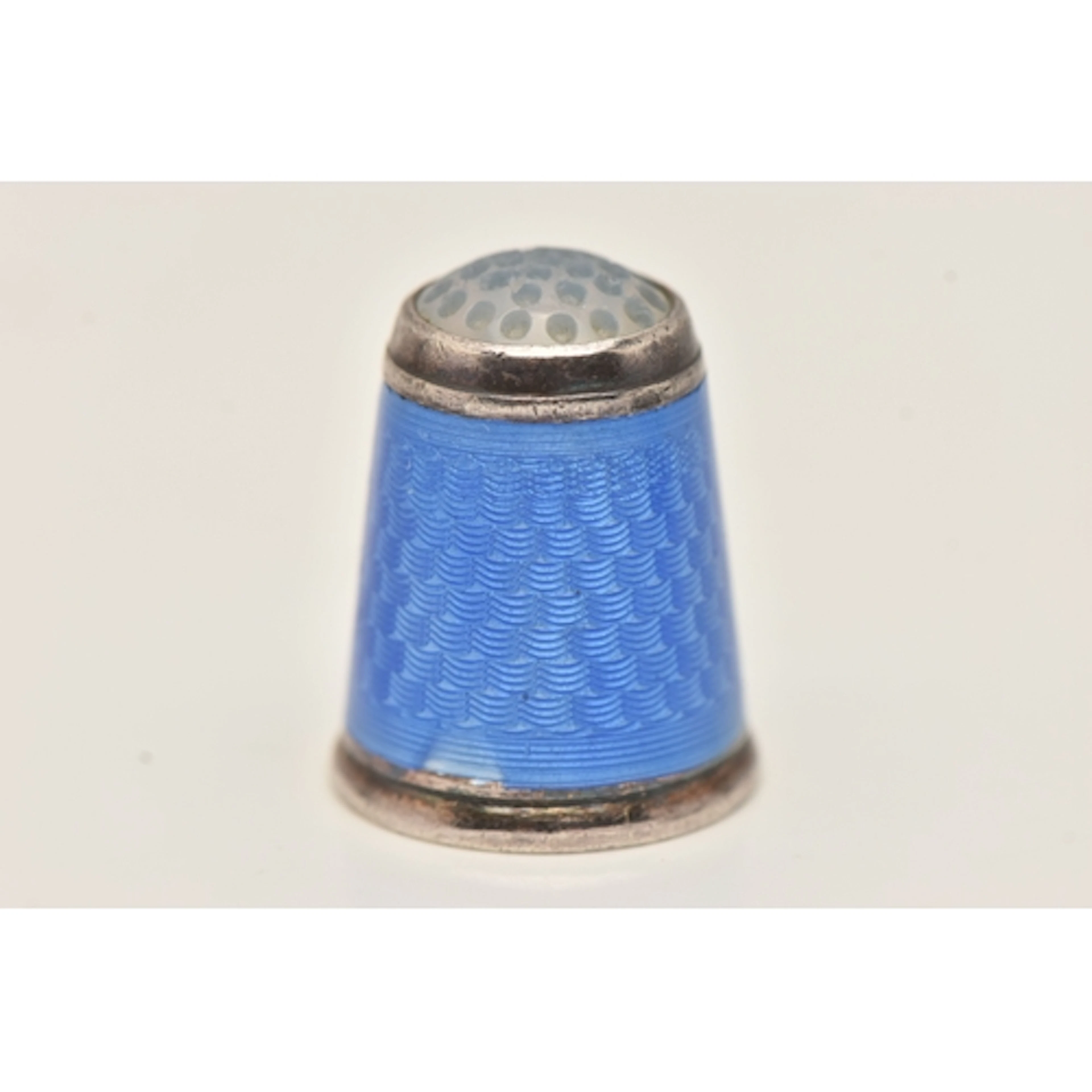 A WHITE METAL ENAMEL THIMBLE, decorated with blue enamel, gi...