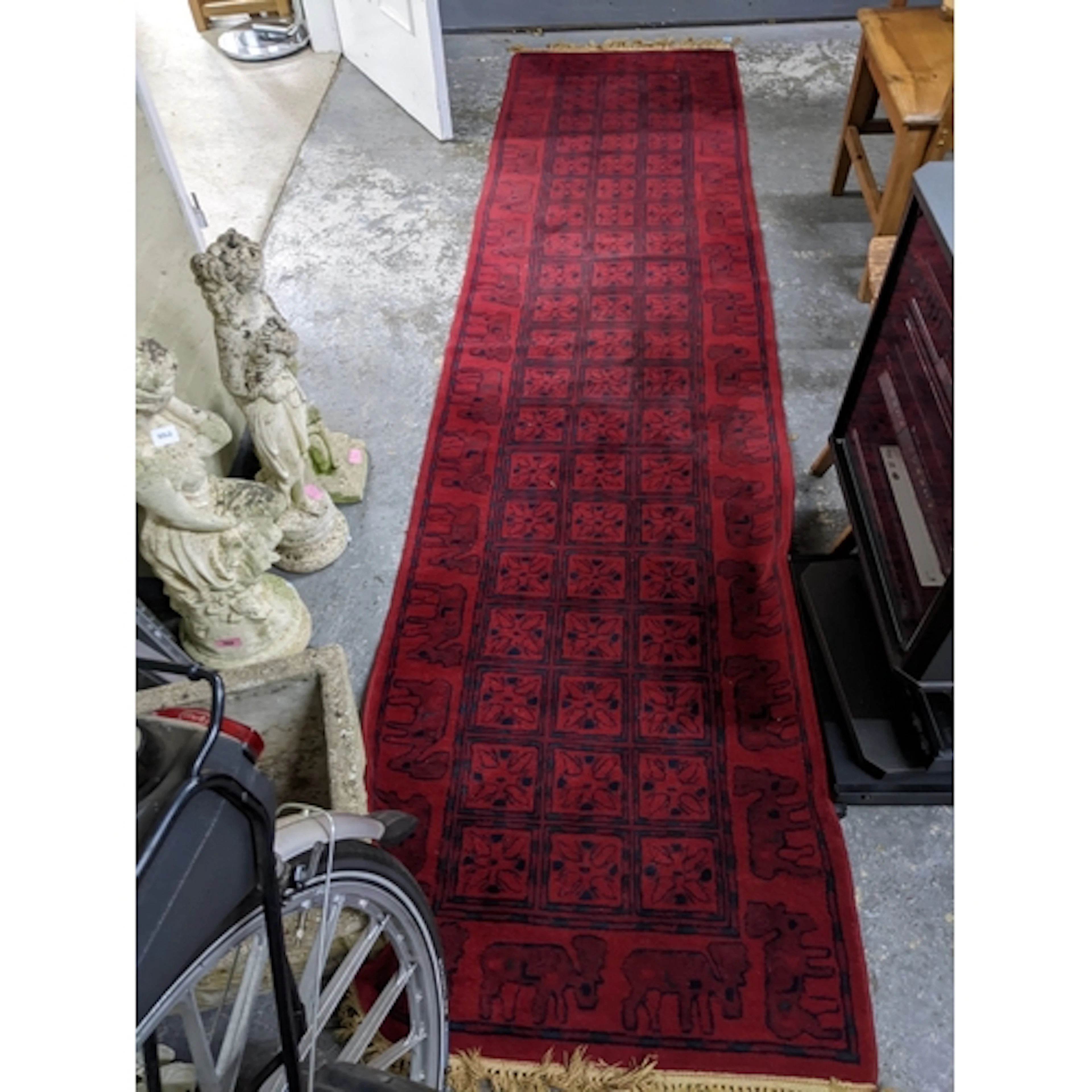 An Afghan deep red ground woollen rug, hand knotted. with th...