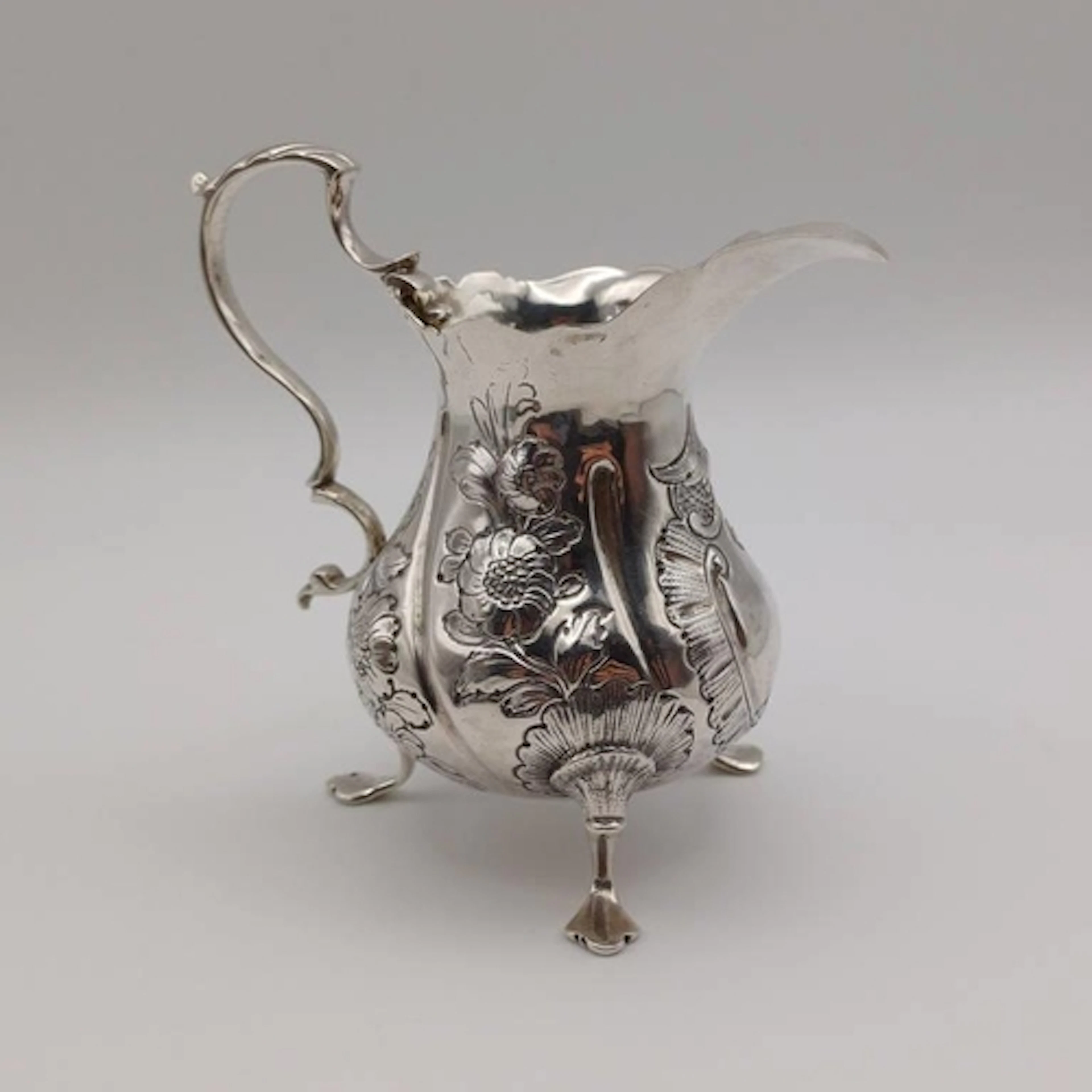 A GEORGIAN SILVER CREAM JUG WITH EMBOSSED FLORAL DECORATION ...