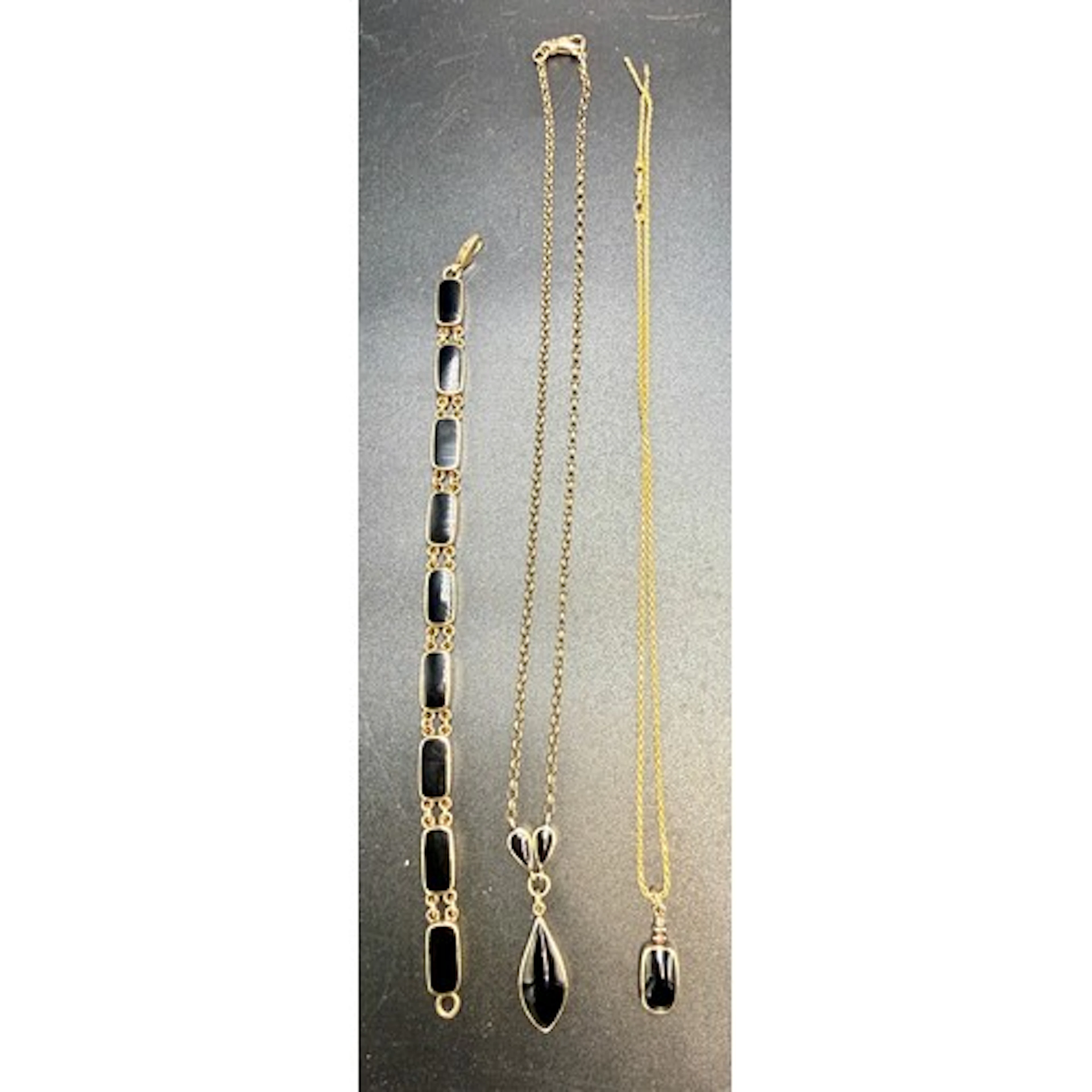 Two nine carat gold pendants set with black stones suspended...