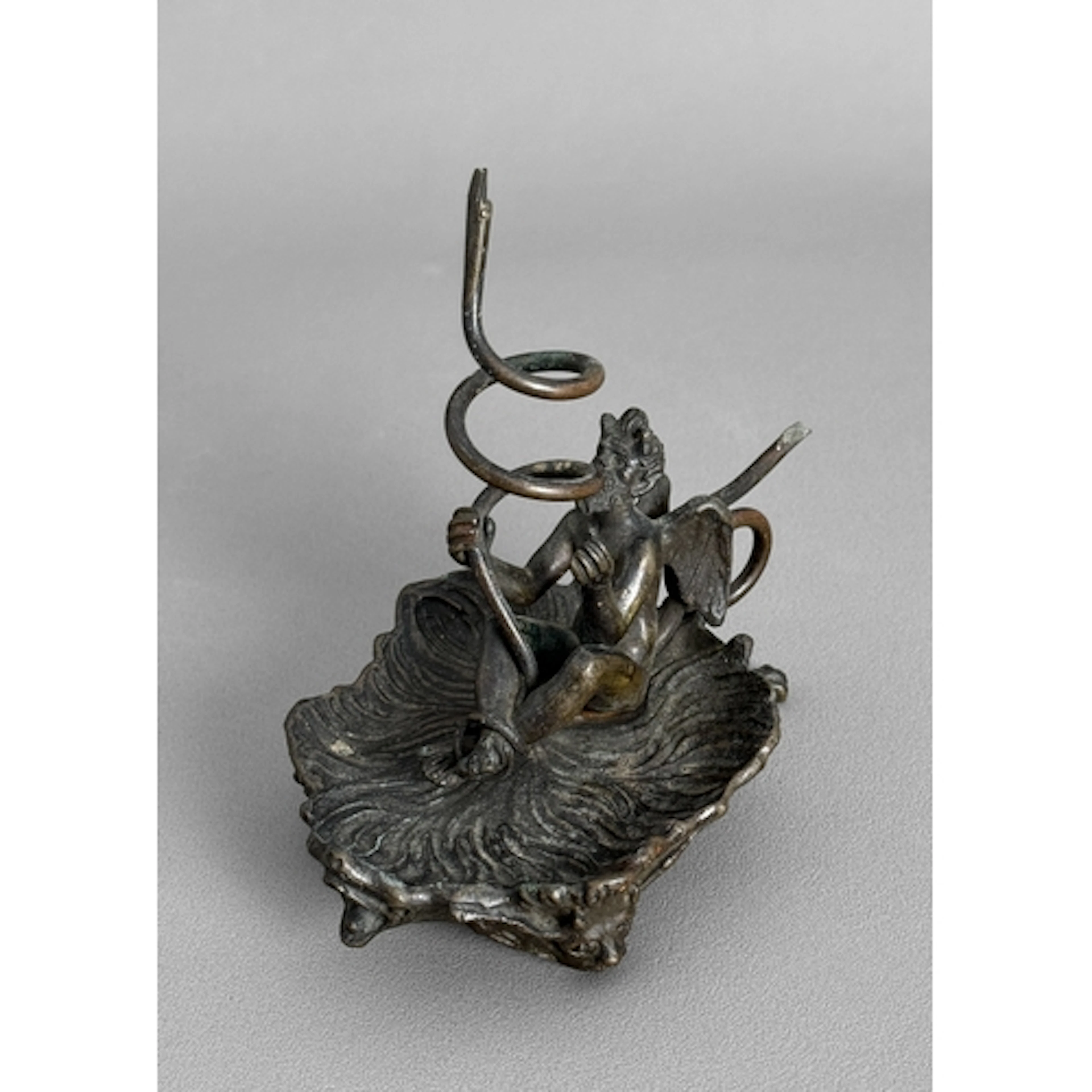 A bronze taperstick - in the form of the devil with a serpen...