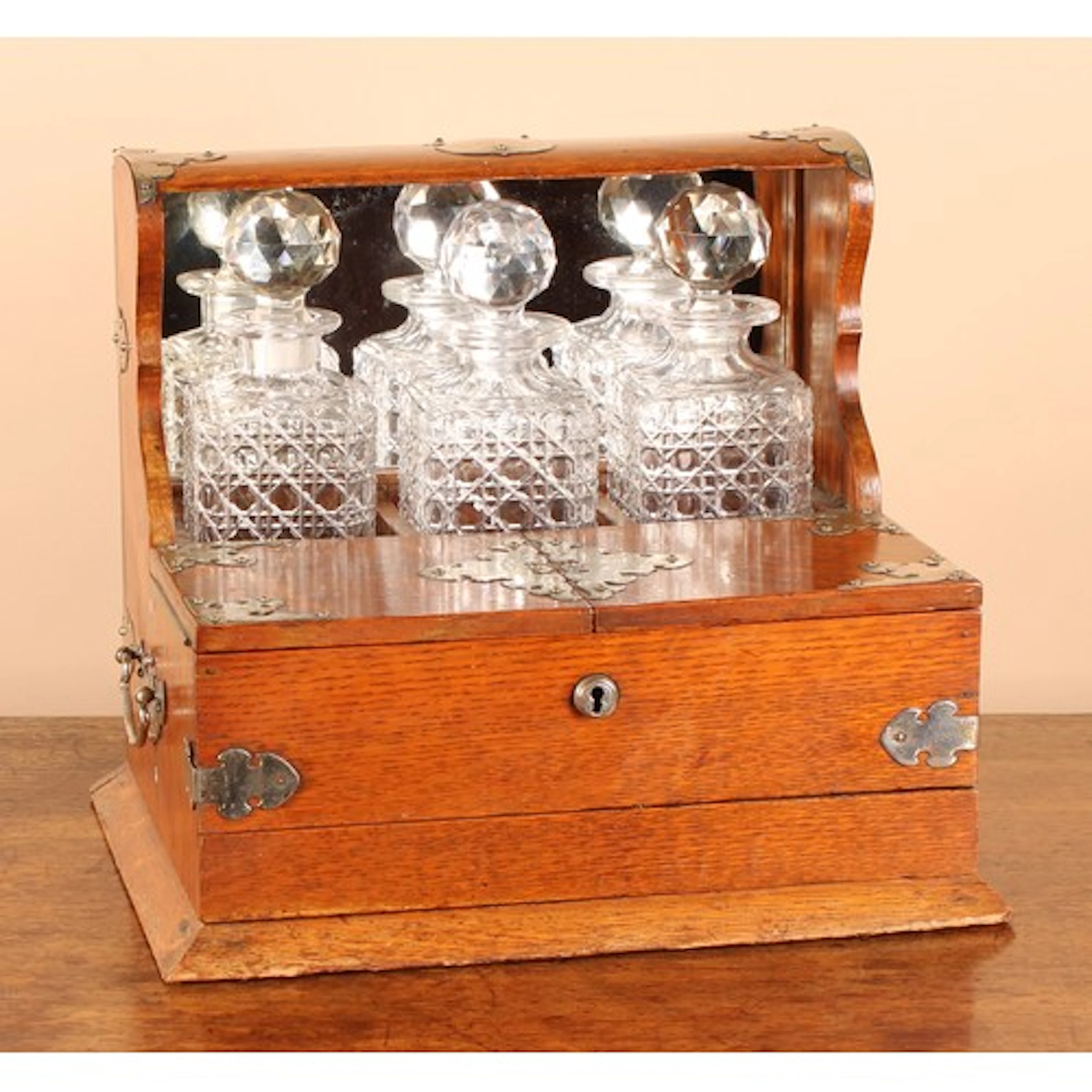 A Victorian oak tantalus, the three decanters restrained wit...