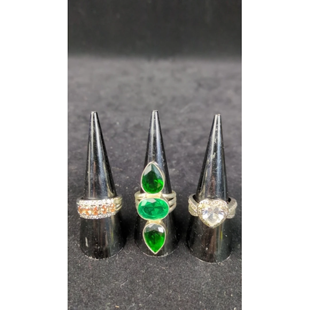 Three silver rings: one set with orange and colourless stone...