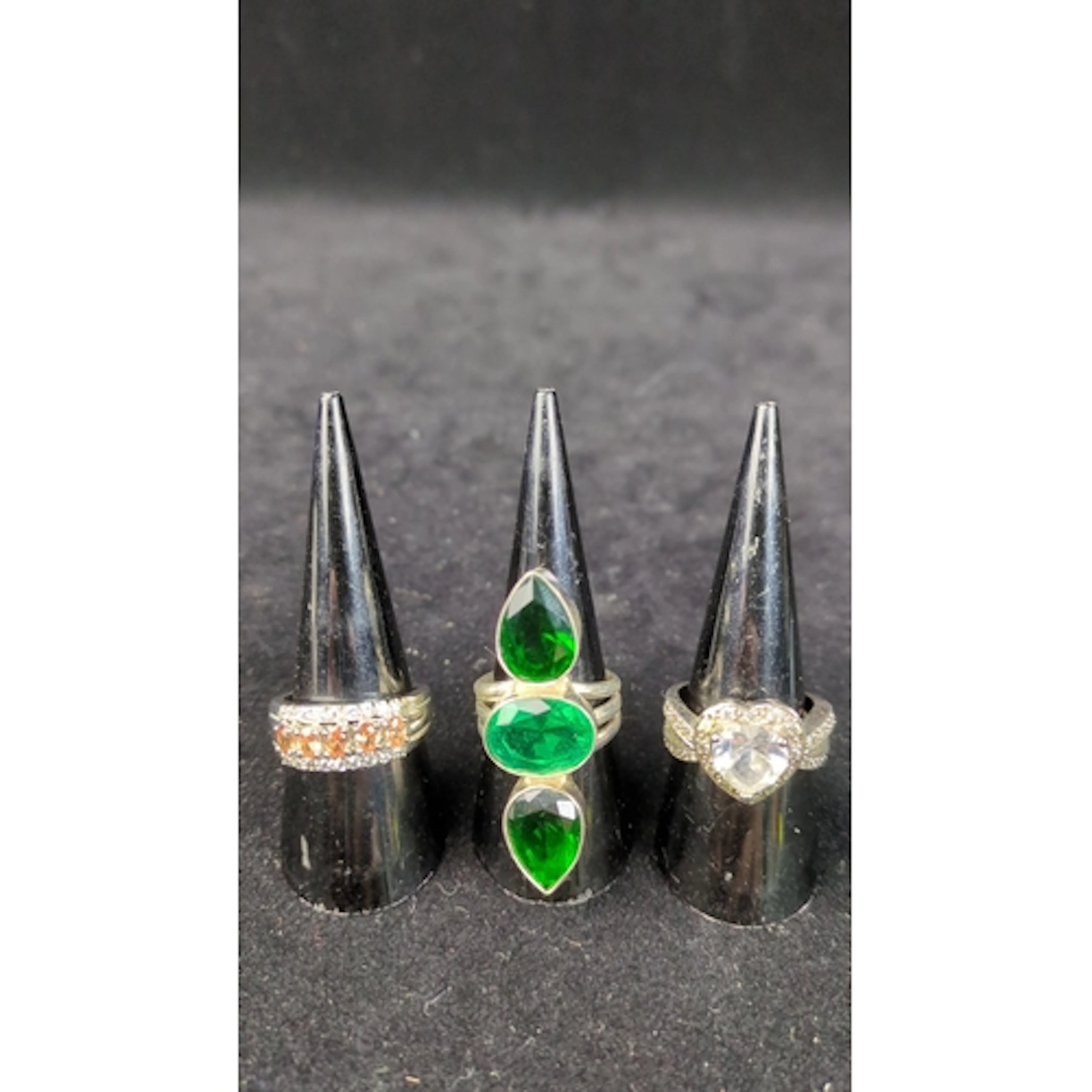 Three silver rings: one set with orange and colourless stone...