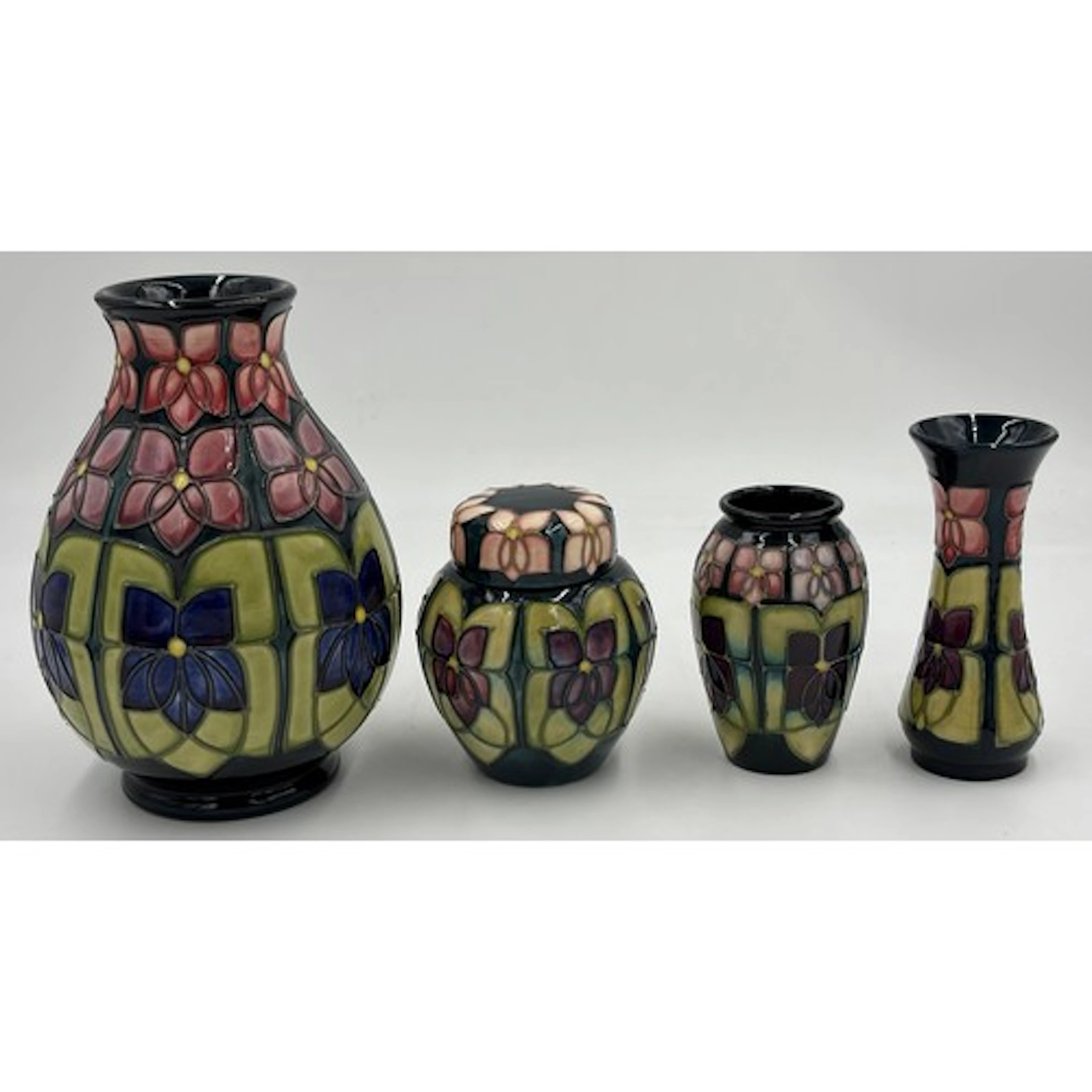 A collection of Moorcroft pottery in Violet pattern designed...