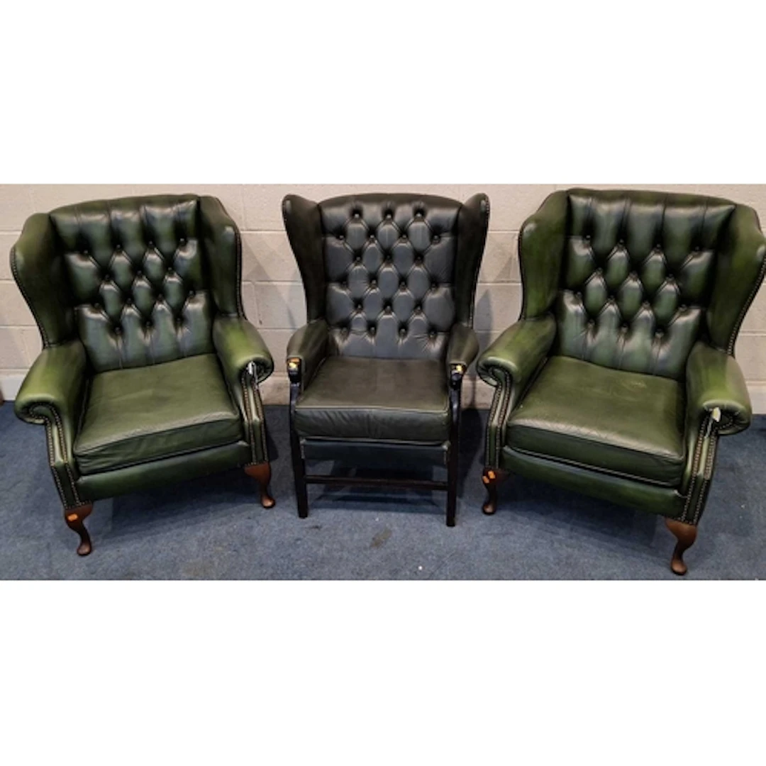 A PAIR OF GREEN LEATHER WINGBACK ARMCHAIRS, with buttoned up...