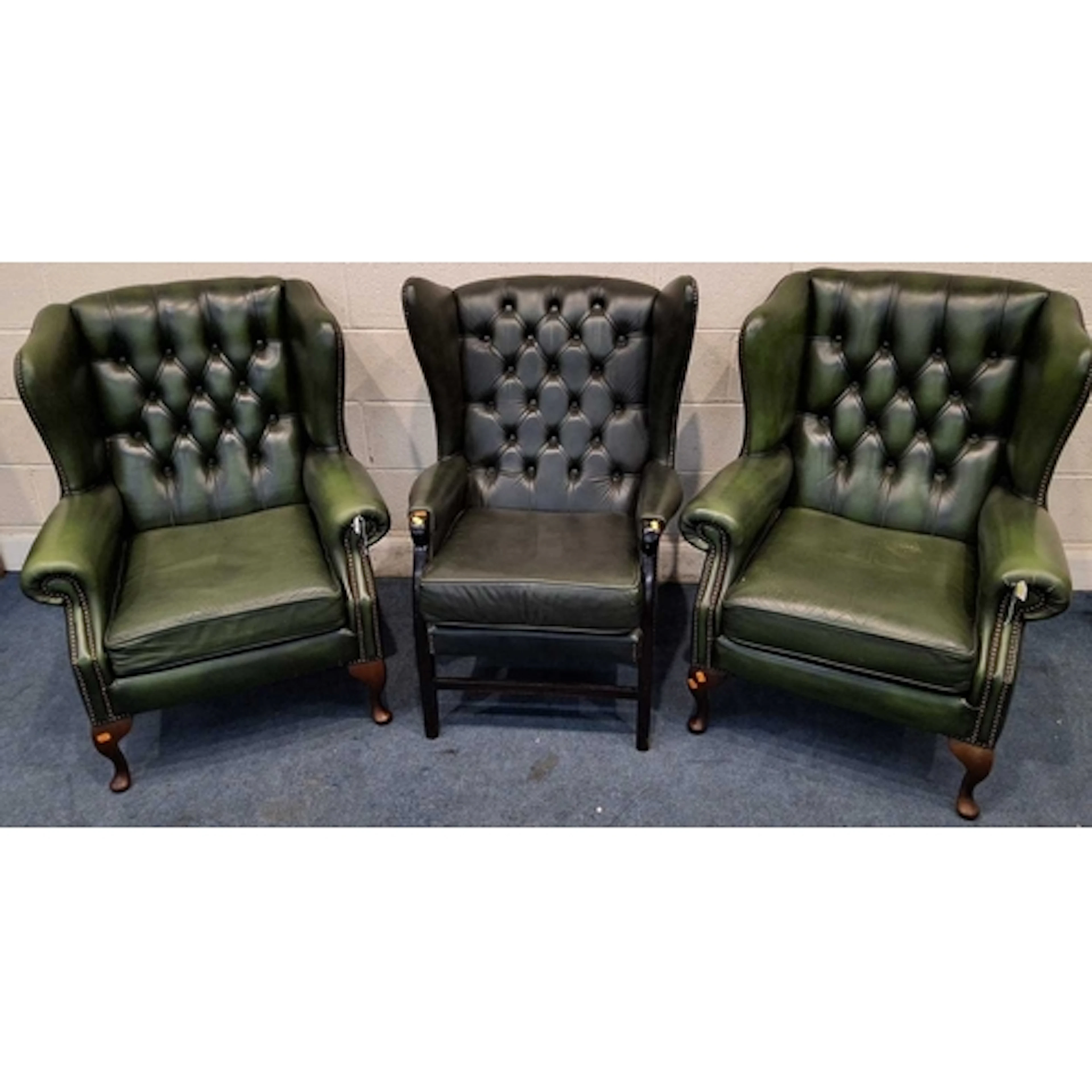 A PAIR OF GREEN LEATHER WINGBACK ARMCHAIRS, with buttoned up...