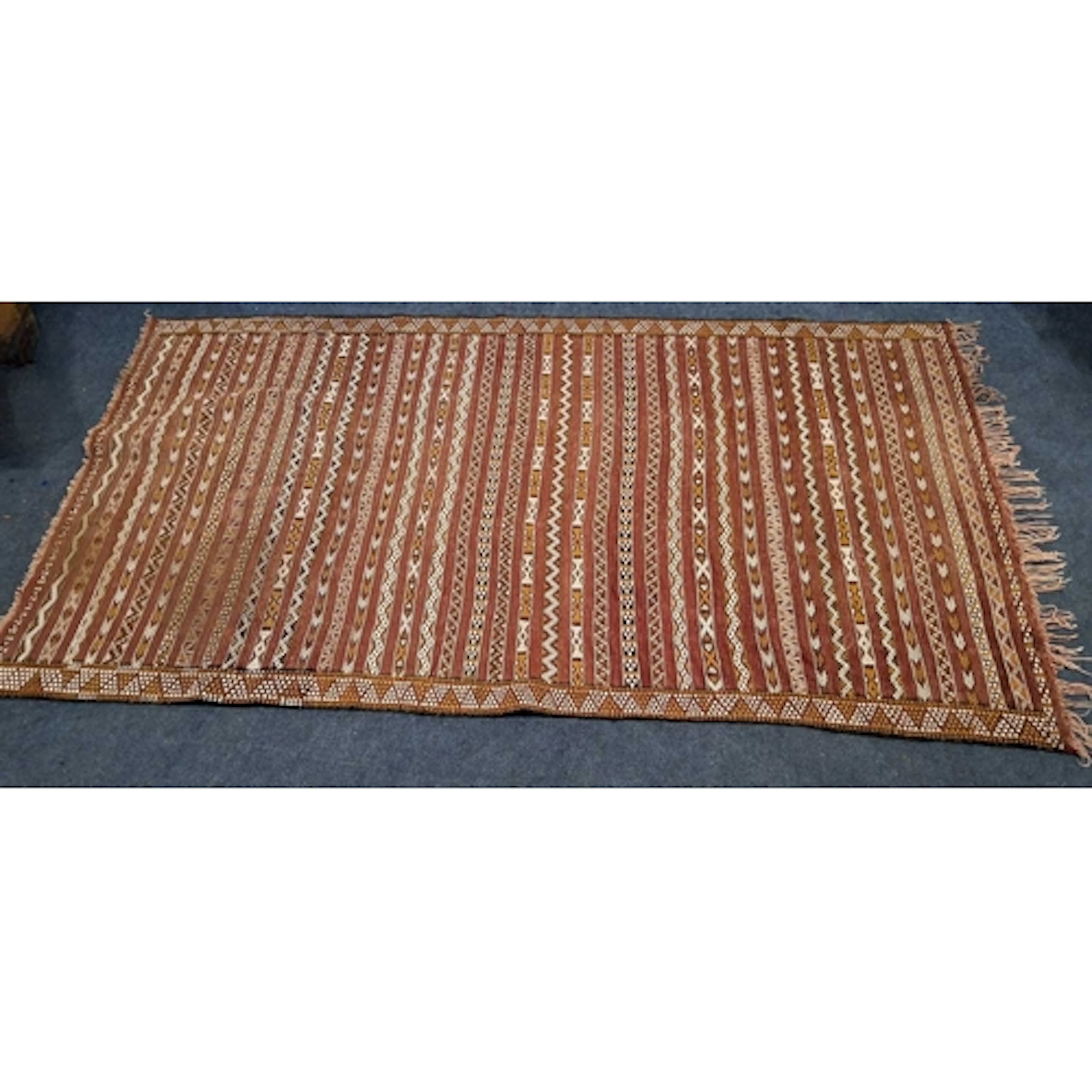 A RED GROUND KILIM RUG, with striped and repeating geometric...