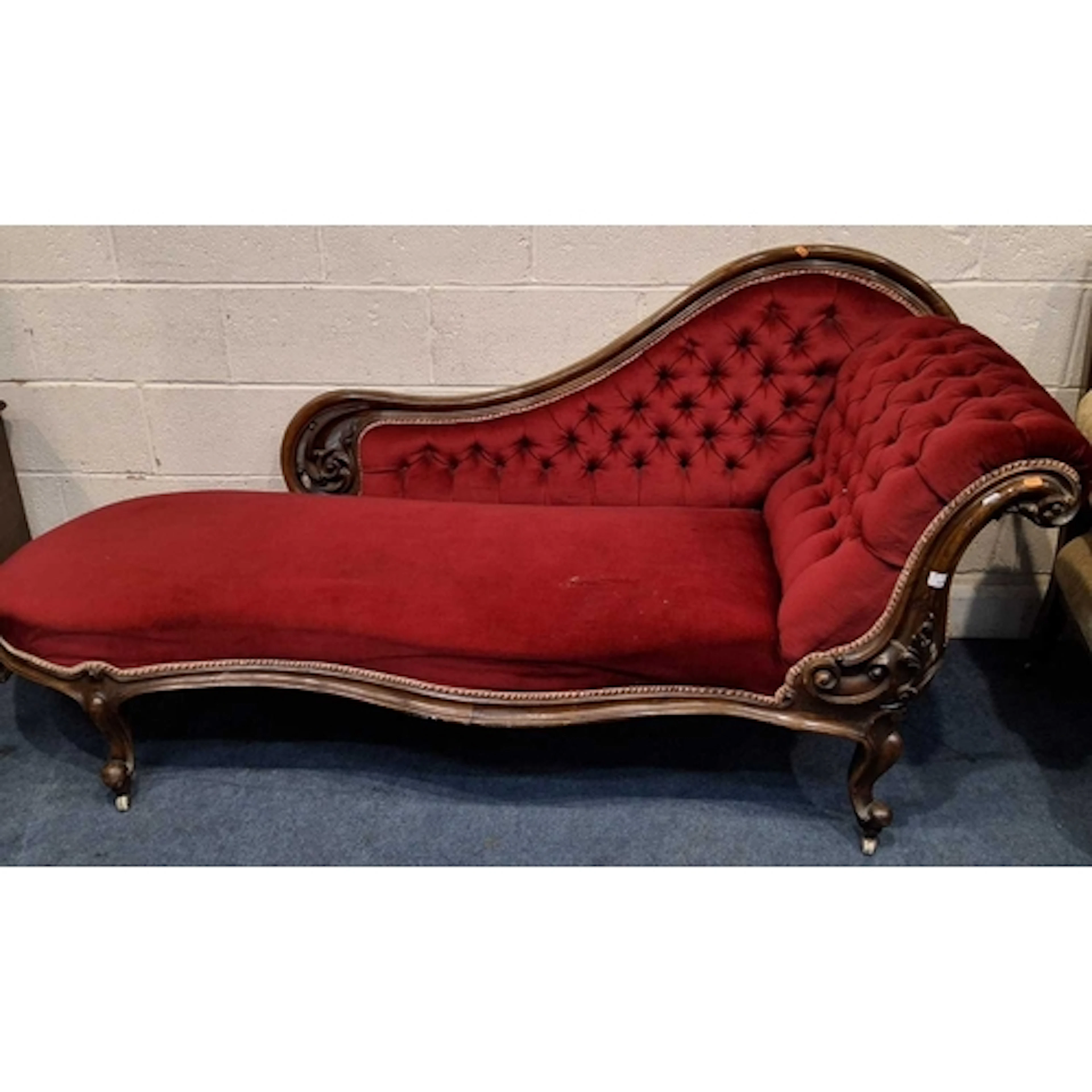 A VICTORIAN CHAISE LONGUE, with a scrolled armrest, carved f...