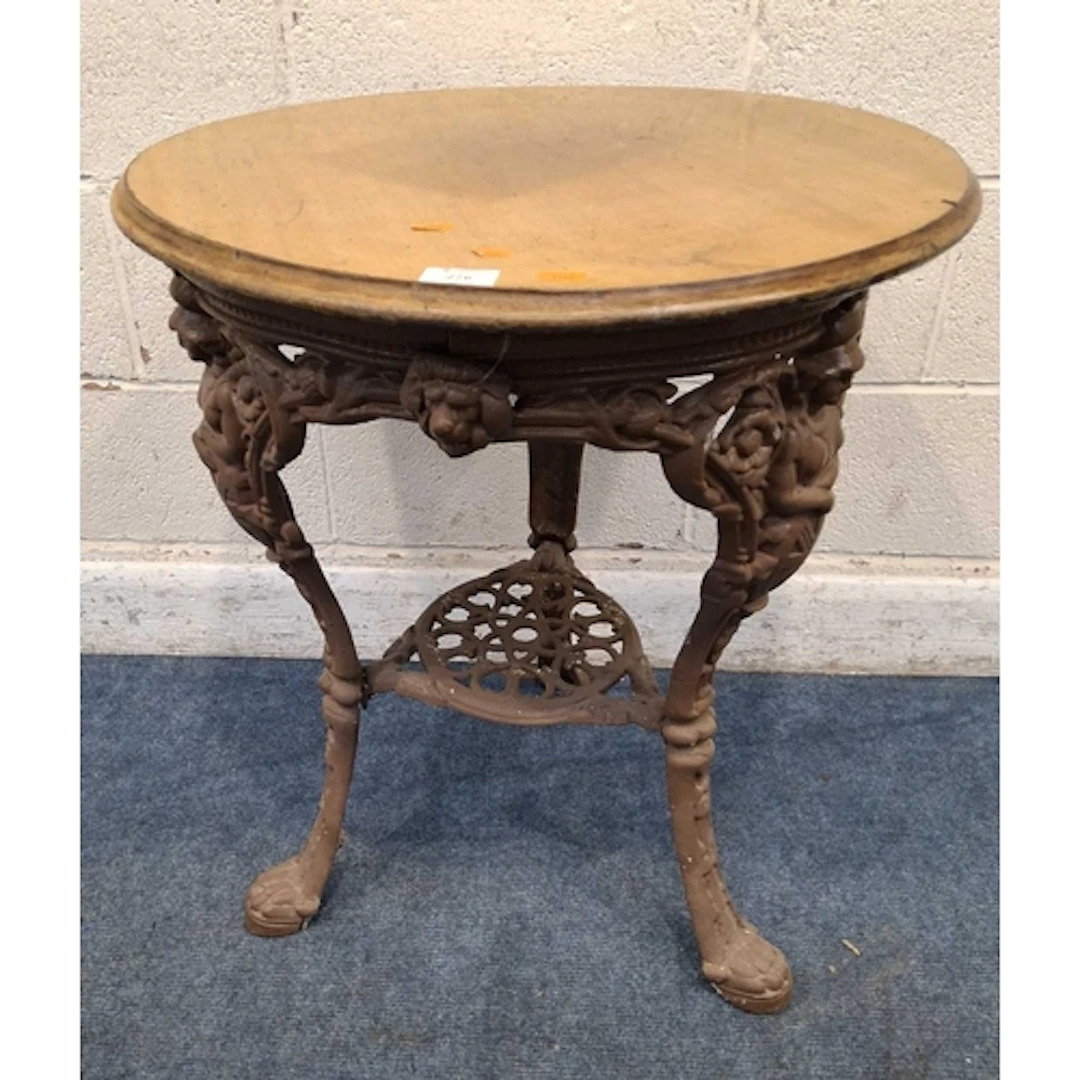 A CAST IRON PUB TABLE, with a wooden top, the base depicting...